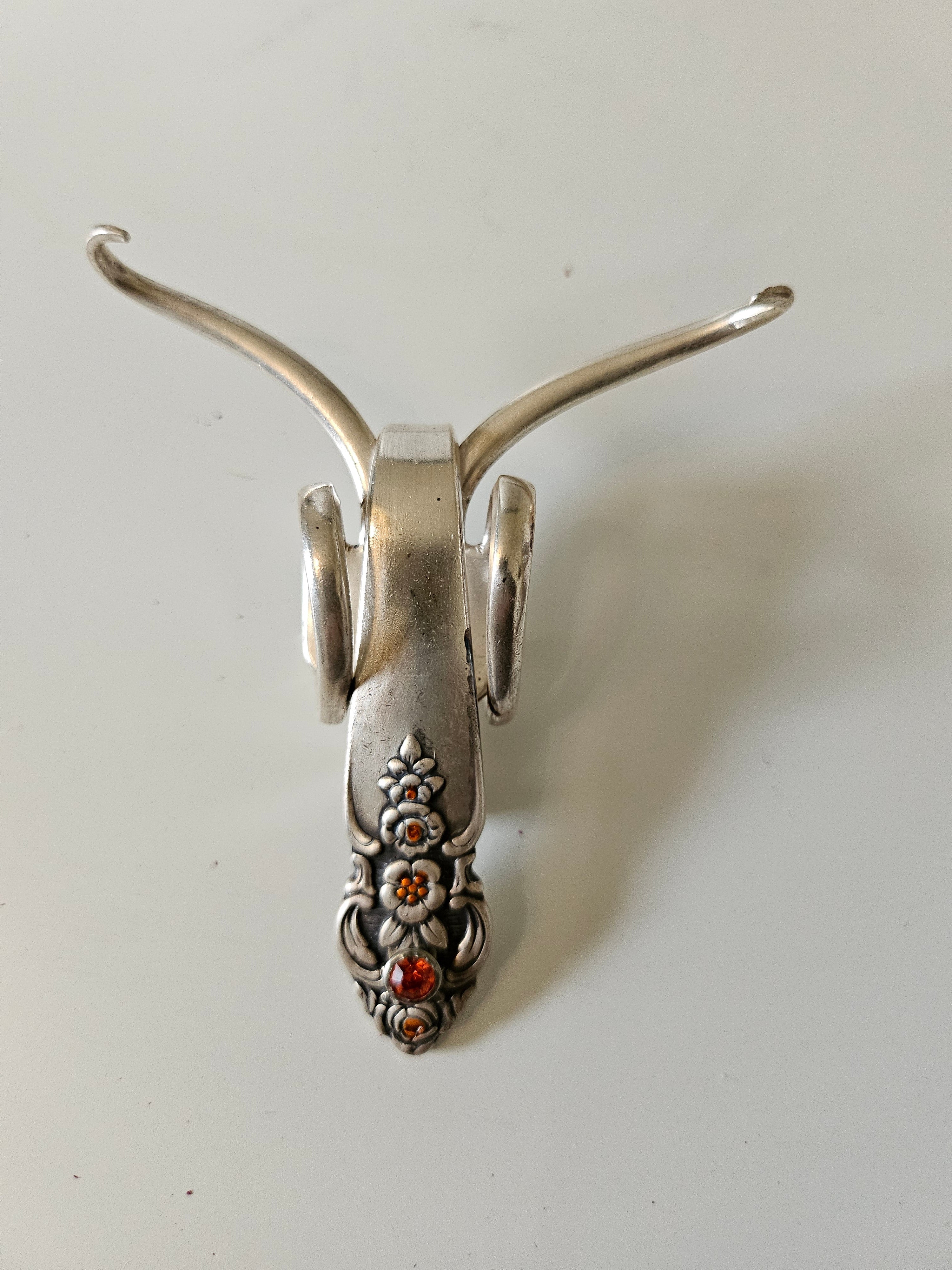 The Jeweled Lucky Fork Cricket is a whimsical, handcrafted sculpture made from repurposed vintage silverware. Each unique piece, shaped from antique forks, captures the charm of crickets—symbols of luck, prosperity, and protection. Adorned with jewels and aged patina, these one-of-a-kind collectibles add artistry, history, and positive energy to any space.