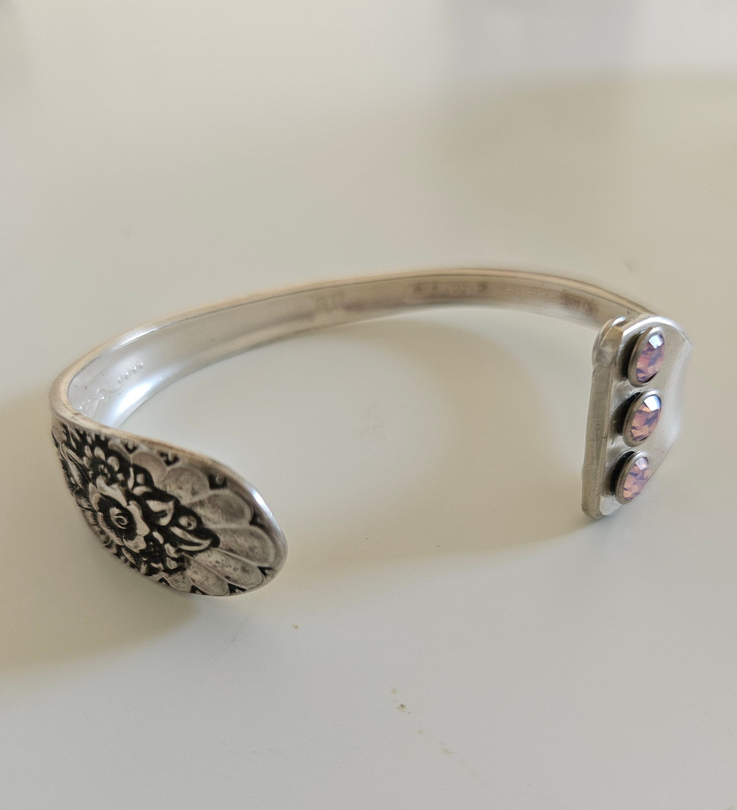 Handcrafted from 1953 Jubilee silverware, this vintage cuff bracelet features delicate floral details and pink crystals for a timeless, romantic sparkle