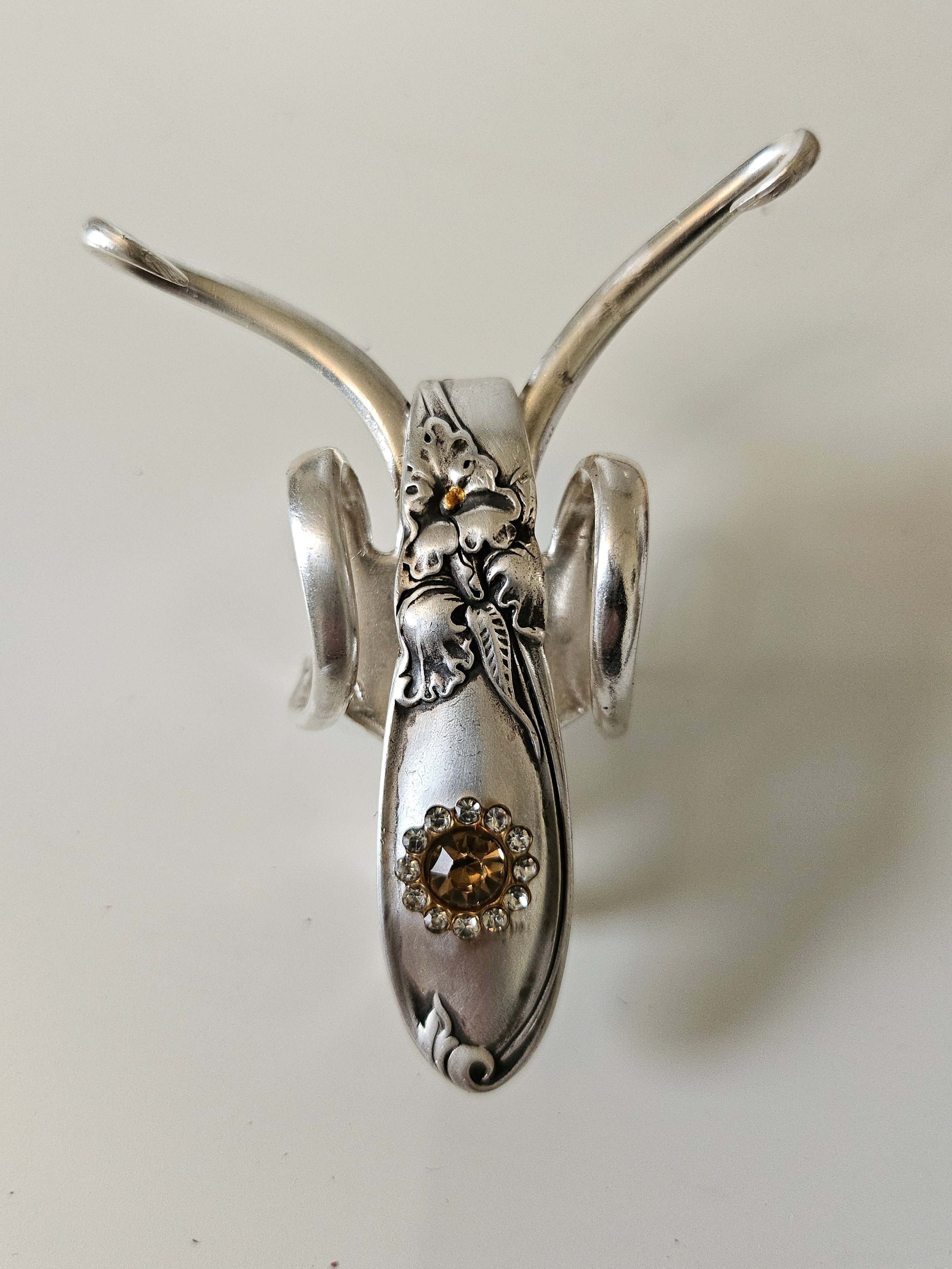 The Jeweled Lucky Fork Cricket is a whimsical, handcrafted sculpture made from repurposed vintage silverware. Each unique piece, shaped from antique forks, captures the charm of crickets—symbols of luck, prosperity, and protection. Adorned with jewels and aged patina, these one-of-a-kind collectibles add artistry, history, and positive energy to any space.