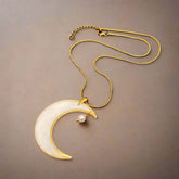 Moon-shaped pendant necklace with real pressed flowers and shell in resin, set in 18K gold-plated brass. Unique, handmade celestial floral jewelry.