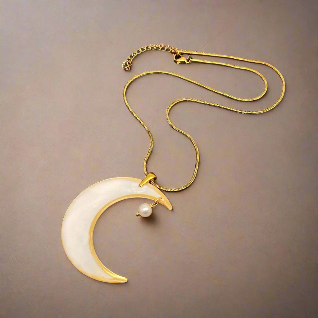 Moon-shaped pendant necklace with real pressed flowers and shell in resin, set in 18K gold-plated brass. Unique, handmade celestial floral jewelry.