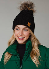 Black diamond cable knit pom hat with natural faux fur pom. Fleece lined for extra warmth and comfort. Classic 100% acrylic design for timeless winter style.
