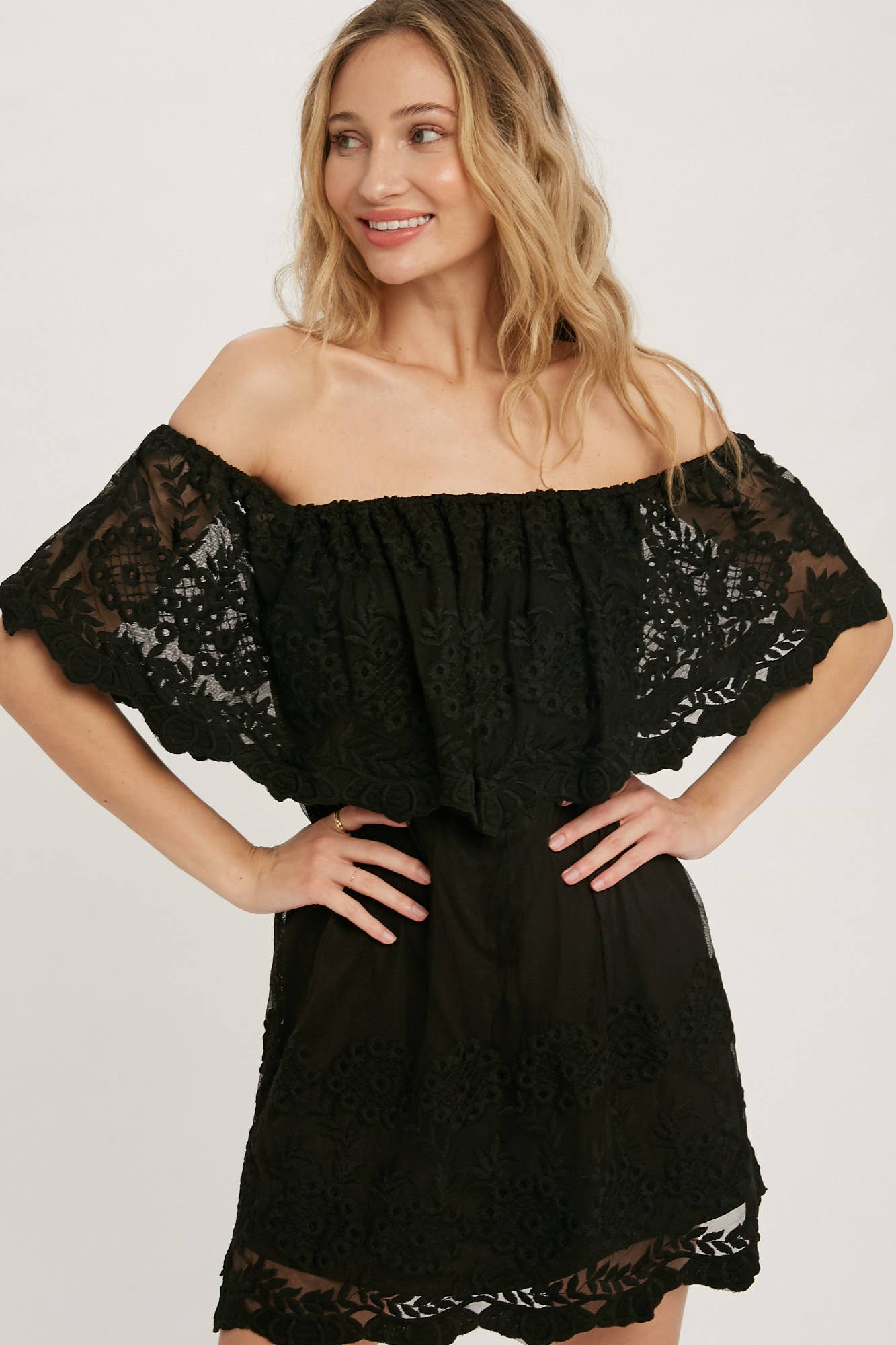 Off-the-shoulder floral lace mini dress with elastic neckline and swingy flounce silhouette. Romantic woven lace, scalloped hem, feminine fit.