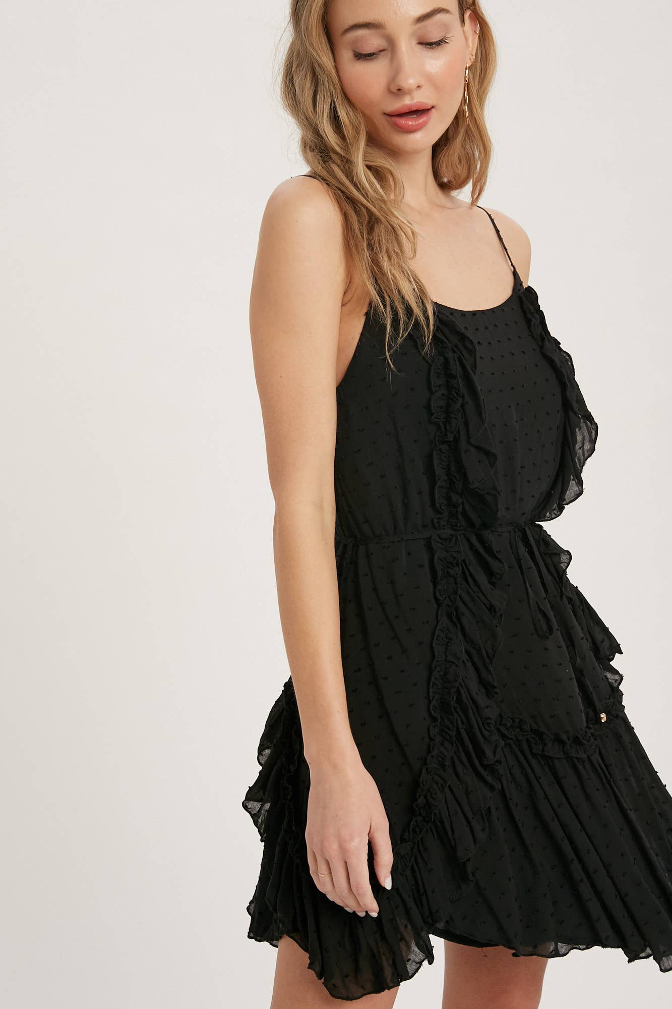 Swiss dot mini dress with ruffle details, lace-up back, adjustable straps & waist tie. Lightweight rayon, perfect for warm days & effortlessly chic looks.