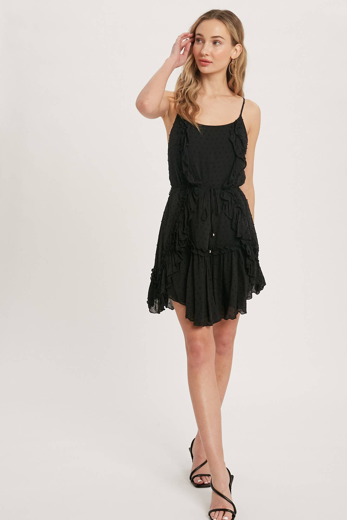 Swiss dot mini dress with ruffle details, lace-up back, adjustable straps & waist tie. Lightweight rayon, perfect for warm days & effortlessly chic looks.