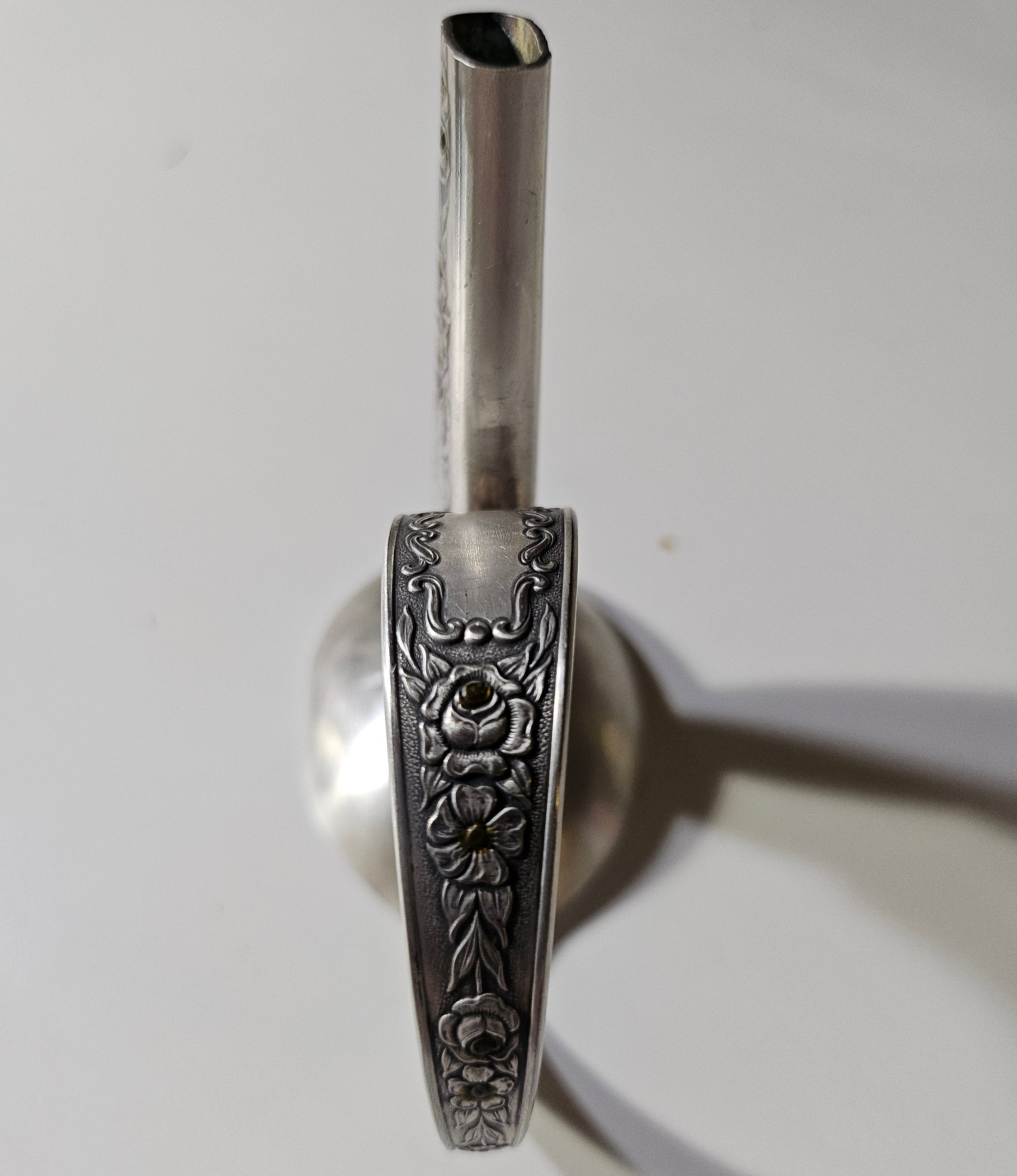 The Salvaged Silver Vintage Bud Vase is a handcrafted décor piece made from authentic Mildred 1936 antique silverware. Repurposed with artistry, it blends vintage charm with sustainability. Each vase is unique, making it a timeless accent for any space. A perfect gift for collectors and eco-conscious decorators, bringing history to modern homes.