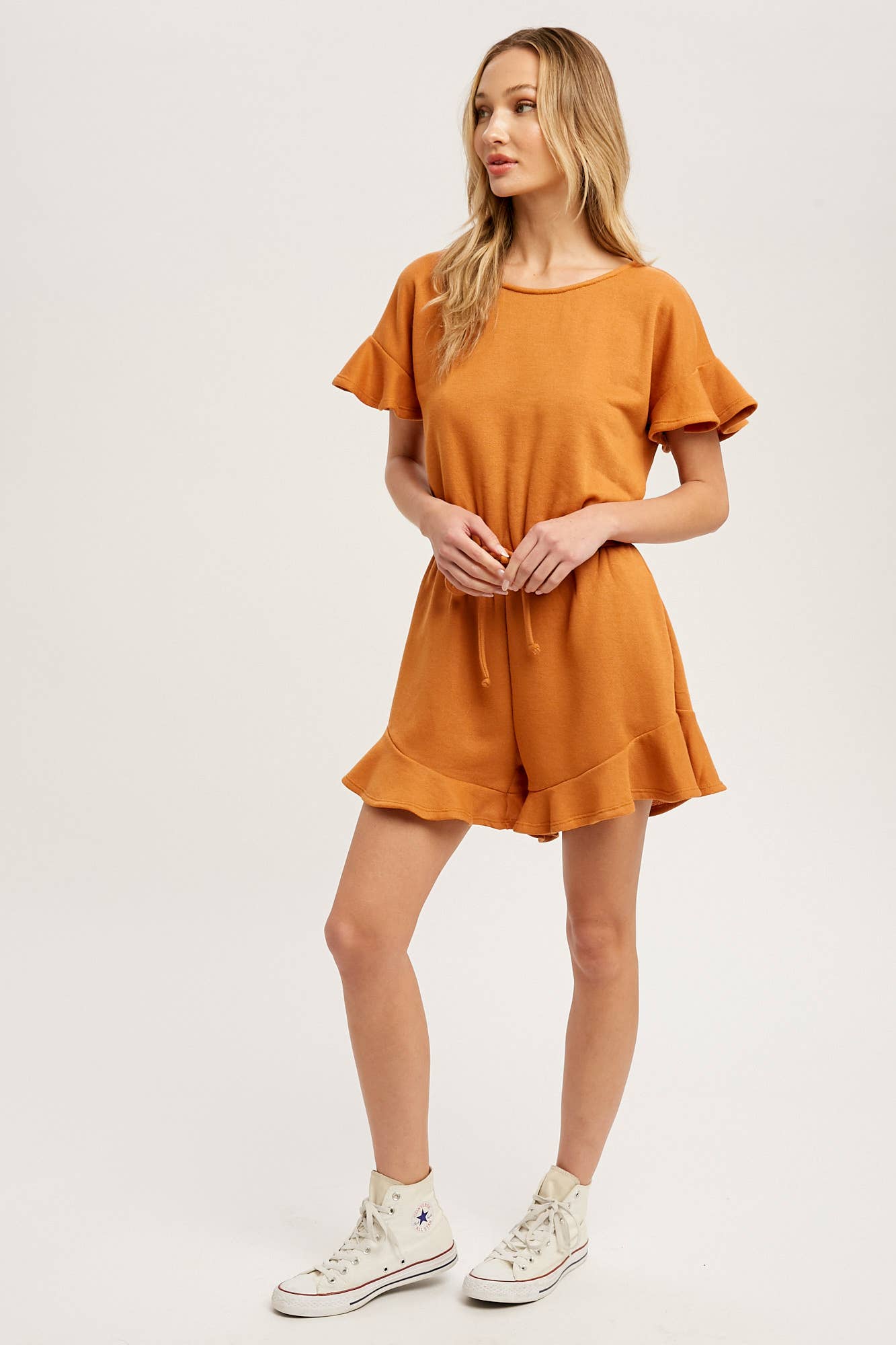 Soft French terry romper with ruffled sleeves, elastic waist, pockets & back button closure. Comfy, cute, and perfect for sunny days or casual outings.