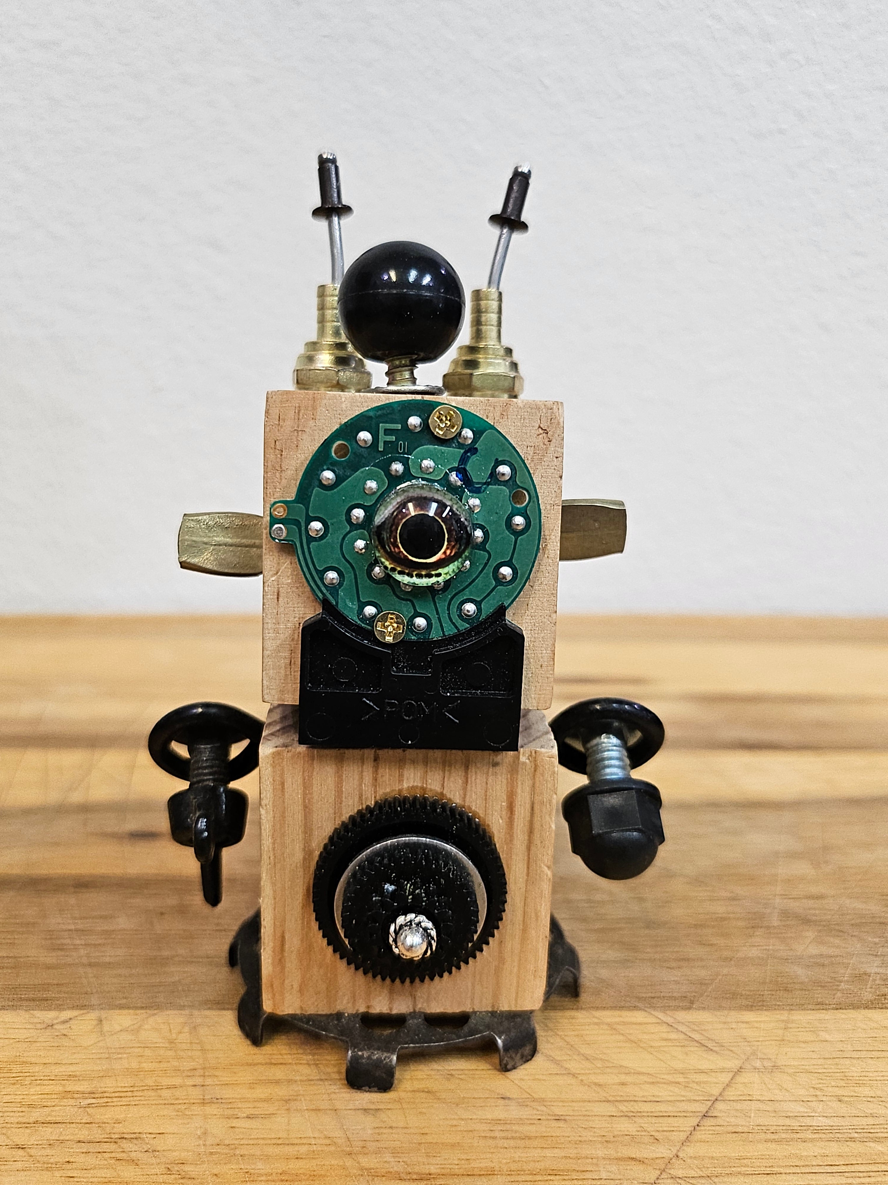 The Handmade Wood Block Steampunk Robot is a unique, decorative figurine crafted from wood with an aged, rustic look. Each robot is one-of-a-kind for display only. Includes a heart-shaped balloon. Available in various sizes, it&