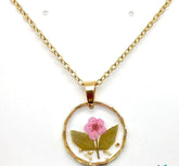 Real pressed flower round pendant necklace in clear resin. Lightweight, nature-inspired, and handcrafted for a unique botanical jewelry statement.