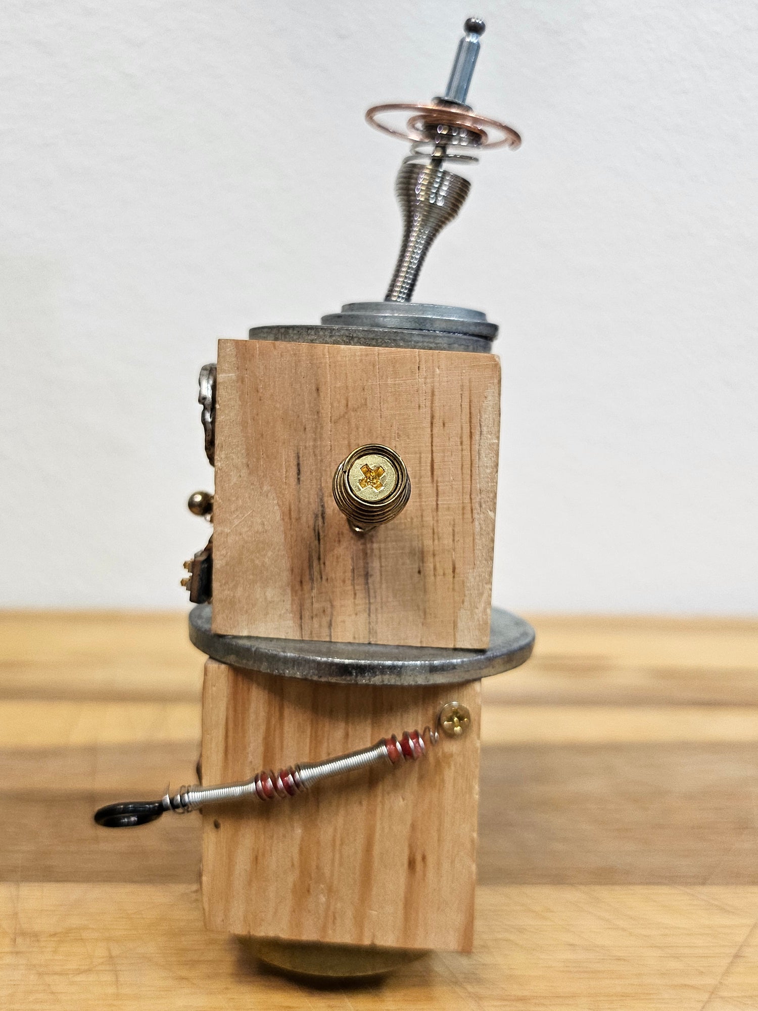 The Handmade Wood Block Steampunk Robot is a unique, decorative figurine crafted from wood with an aged, rustic look. Each robot is one-of-a-kind for display only. Includes a heart-shaped balloon. Available in various sizes, it&