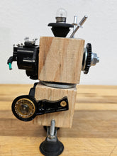 The Handmade Wood Block Steampunk Robot is a unique, decorative figurine crafted from wood with an aged, rustic look. Each robot is one-of-a-kind for display only. Includes a heart-shaped balloon. Available in various sizes, it&