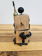 The Handmade Wood Block Steampunk Robot is a unique, decorative figurine crafted from wood with an aged, rustic look. Each robot is one-of-a-kind for display only. Includes a heart-shaped balloon. Available in various sizes, it&