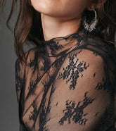 Elegant sheer mesh lace top with floral embroidery, mock neck & thumbhole sleeves. Perfect for layering or nights out. Romantic & versatile style.