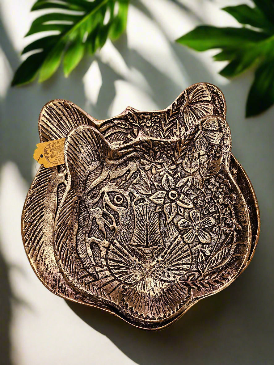 The Tiger Embossed Metal Tray is a luxurious and durable 16 cm x 14.5 cm catchall dish with a golden finish and intricate tiger head design. Perfect for organizing jewelry, keys, or coins, it adds a regal touch to any space. Ideal as a functional decor piece or a thoughtful gift for art and animal lovers.