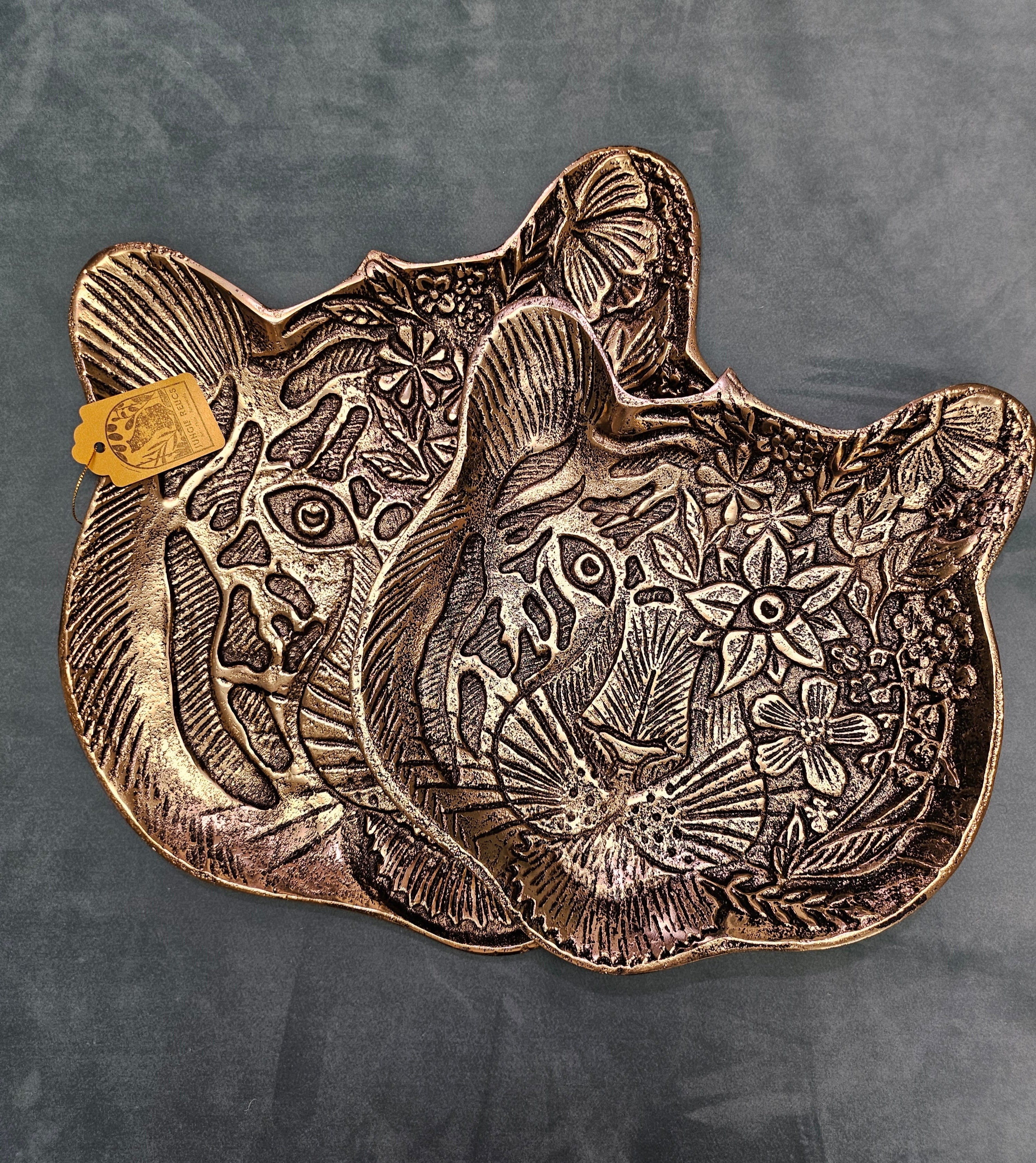 The Tiger Embossed Metal Tray is a luxurious and durable 16 cm x 14.5 cm catchall dish with a golden finish and intricate tiger head design. Perfect for organizing jewelry, keys, or coins, it adds a regal touch to any space. Ideal as a functional decor piece or a thoughtful gift for art and animal lovers