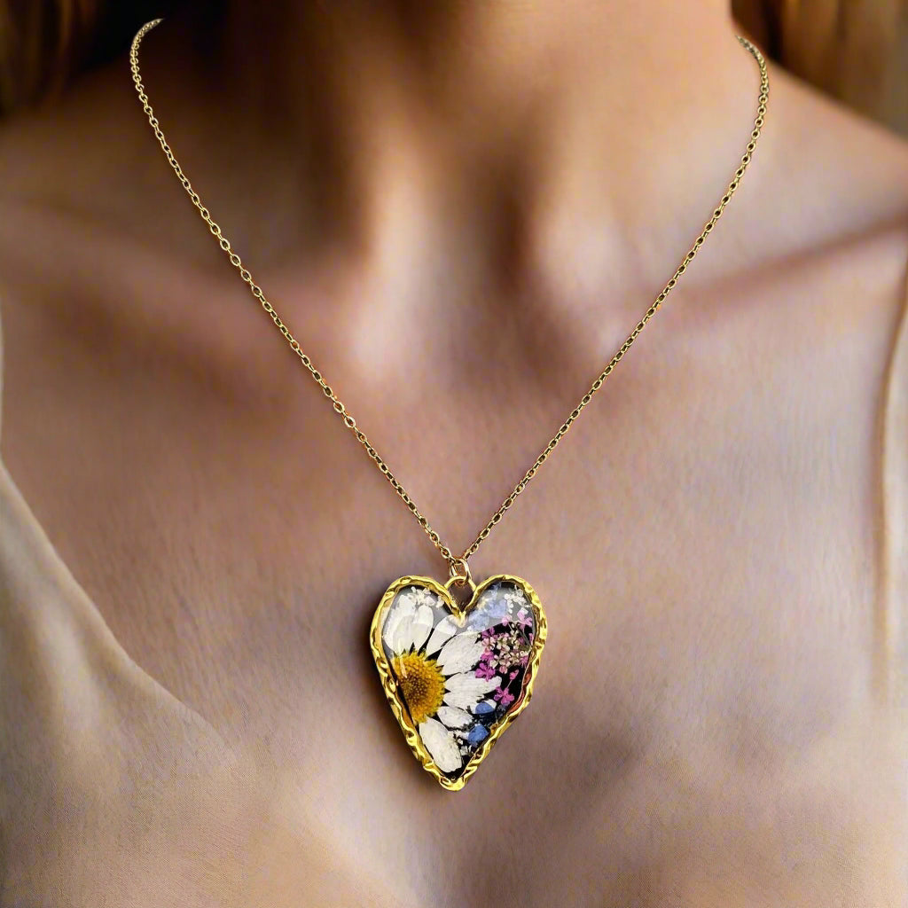 Heart-shaped necklace with real pressed flowers in resin, set in 18K gold-plated copper. Unique, handmade botanical jewelry with stainless steel chain.