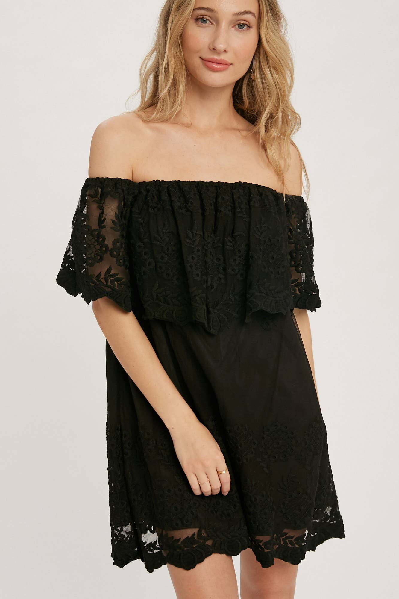 Off-the-shoulder floral lace mini dress with elastic neckline and swingy flounce silhouette. Romantic woven lace, scalloped hem, feminine fit.