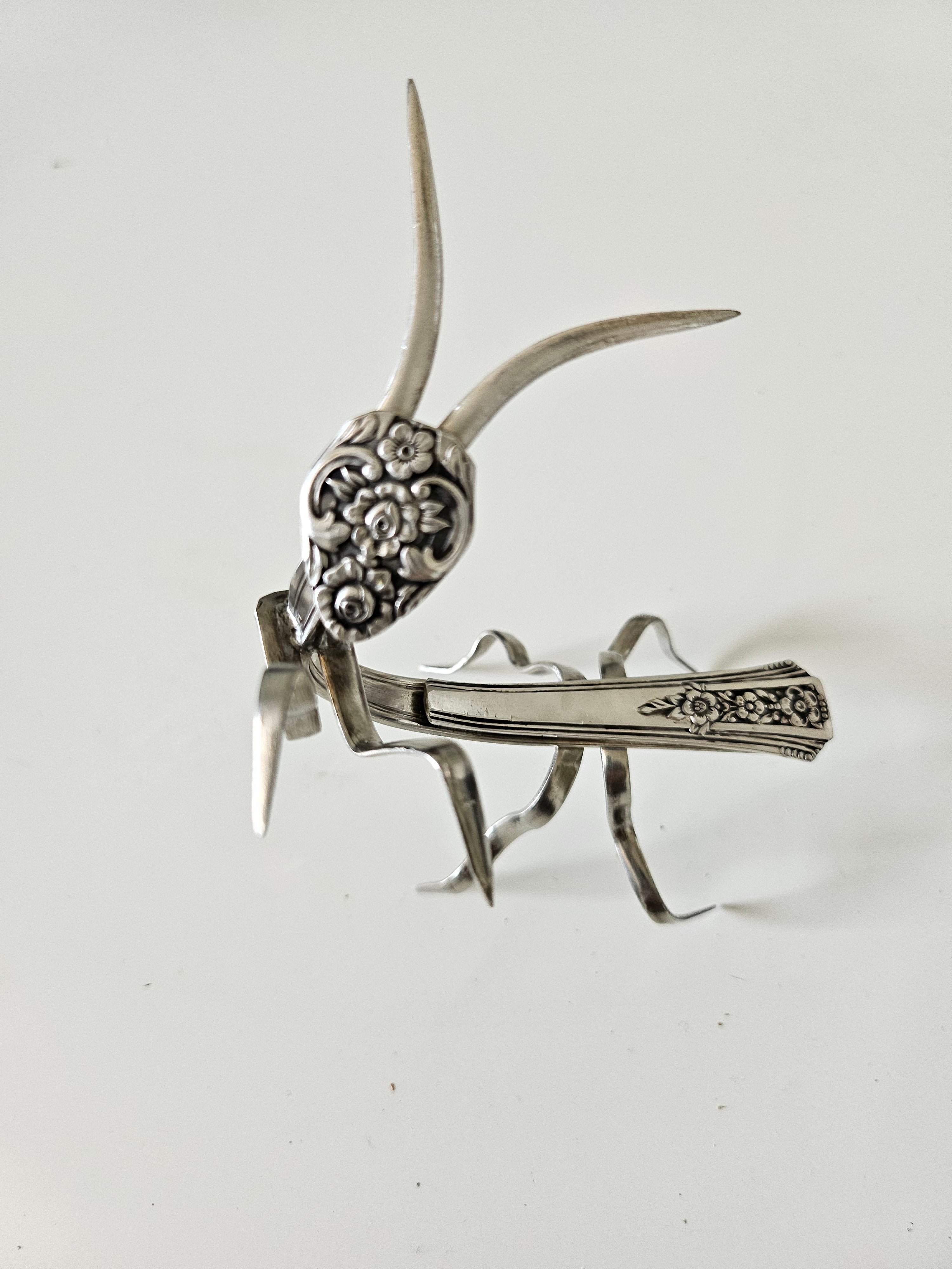Handcrafted 5" x 4" praying mantis sculpture made from vintage silverware. Unique, whimsical art with gemstone accents and aged patina for mindful décor.