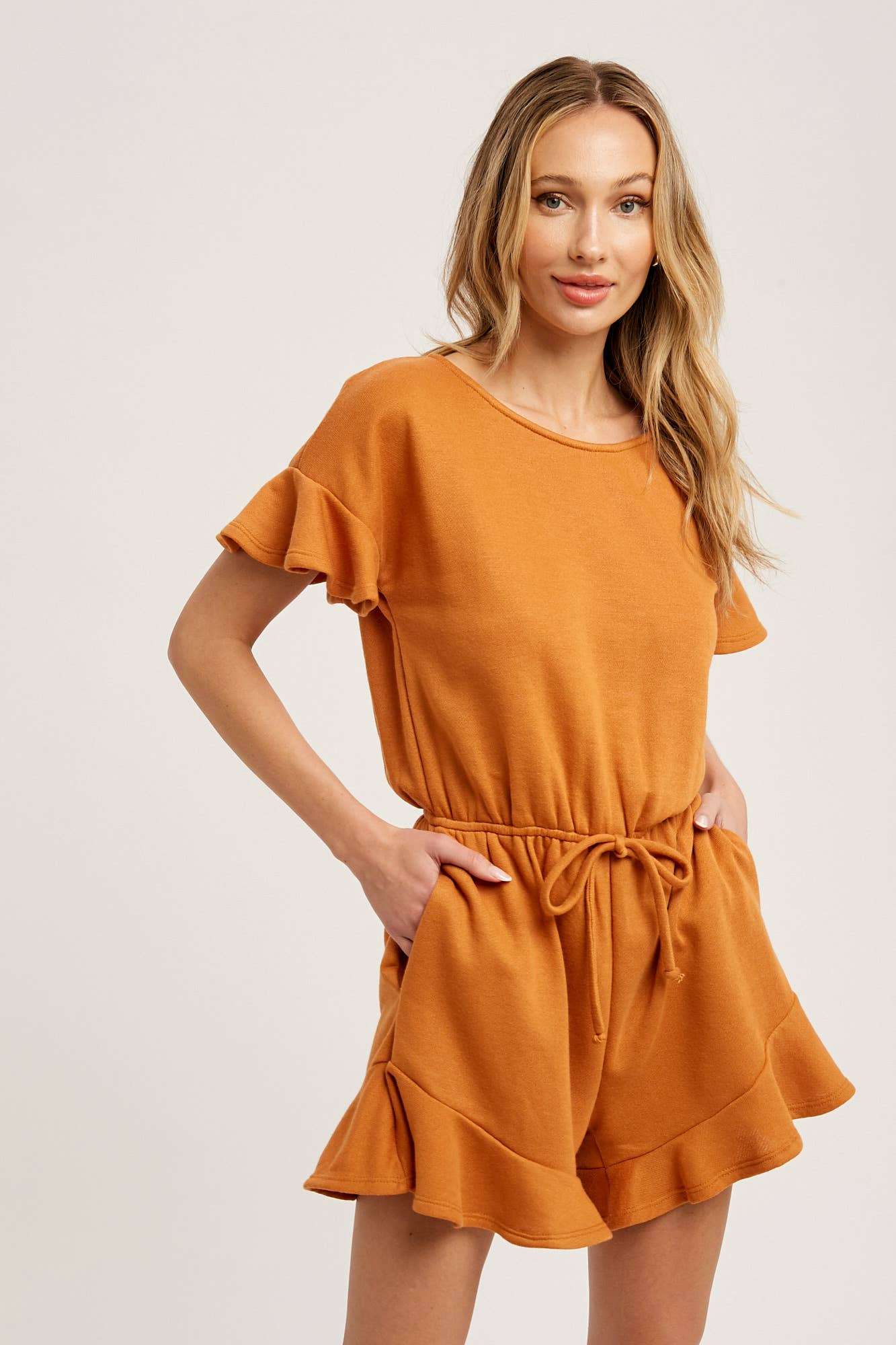 Soft French terry romper with ruffled sleeves, elastic waist, pockets & back button closure. Comfy, cute, and perfect for sunny days or casual outings.