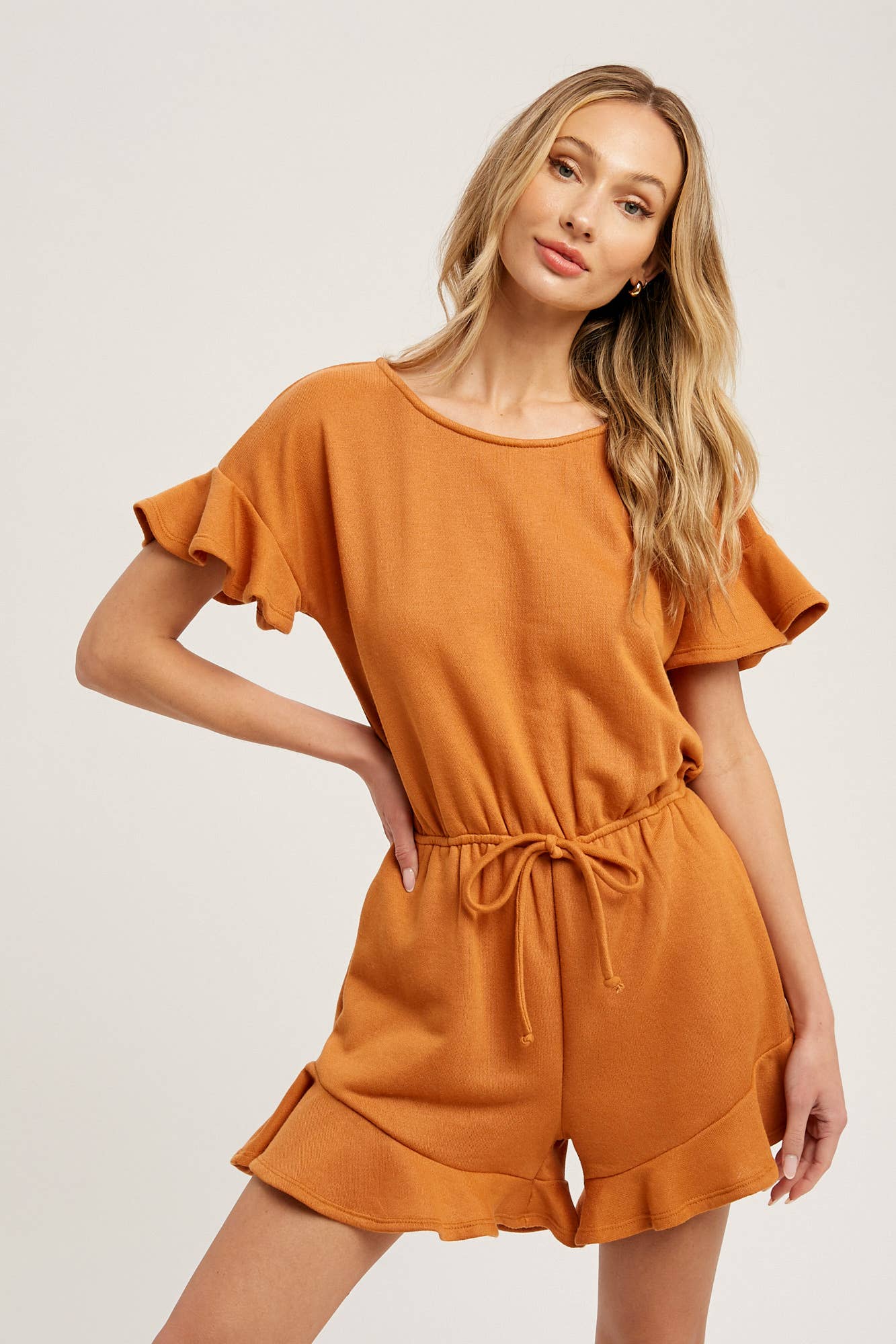 Soft French terry romper with ruffled sleeves, elastic waist, pockets & back button closure. Comfy, cute, and perfect for sunny days or casual outings.
