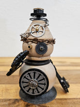The Handmade Wood Block Steampunk Robot is a unique, decorative figurine crafted from wood with an aged, rustic look. Each robot is one-of-a-kind for display only. Includes a heart-shaped balloon. Available in various sizes, it&