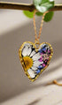 Heart-shaped necklace with real pressed flowers in resin, set in 18K gold-plated copper. Unique, handmade botanical jewelry with stainless steel chain.
