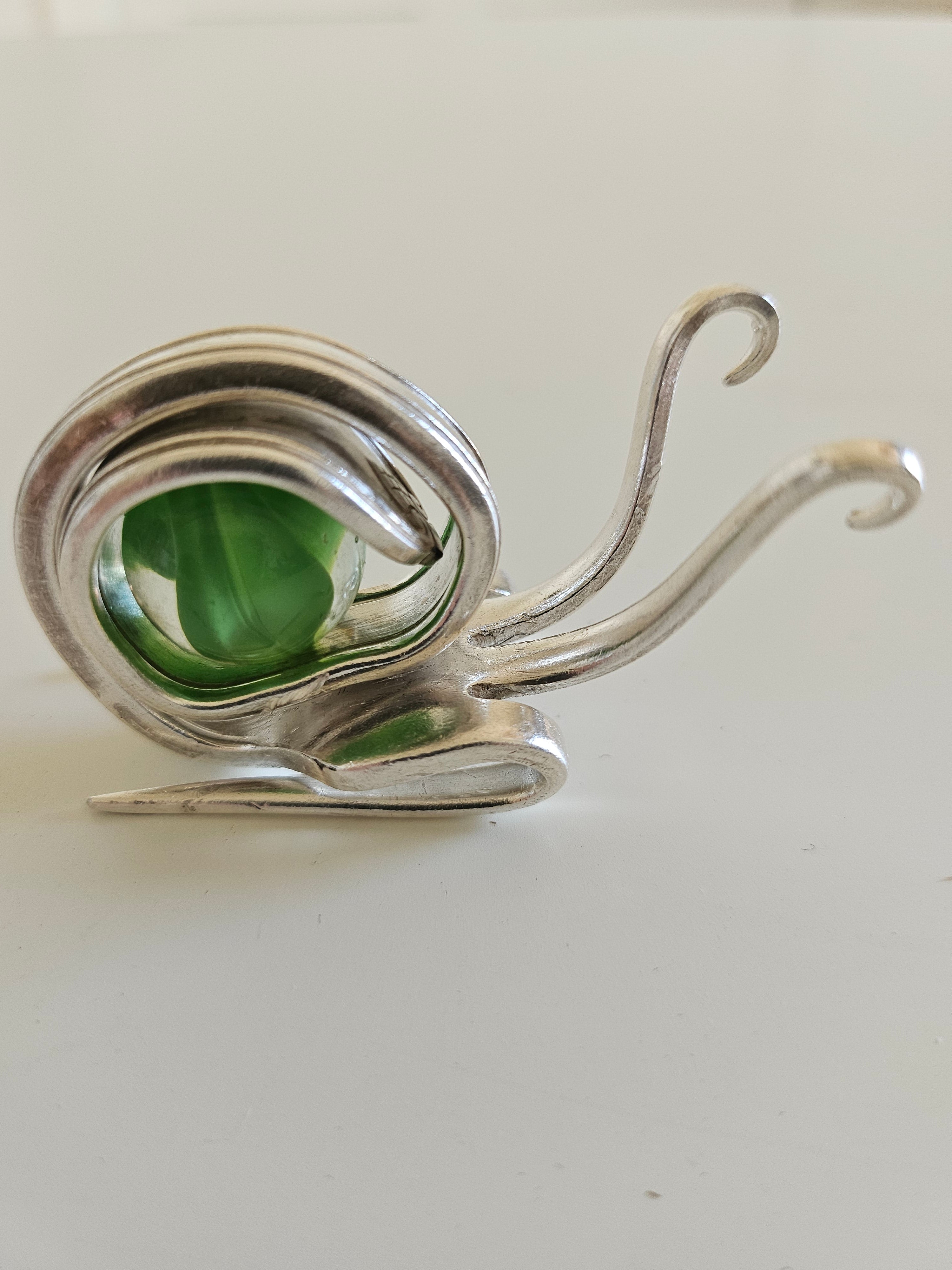 Handcrafted from vintage silverware, these whimsical snails feature shimmering glass orb shells—each a one-of-a-kind symbol of patience and charm.