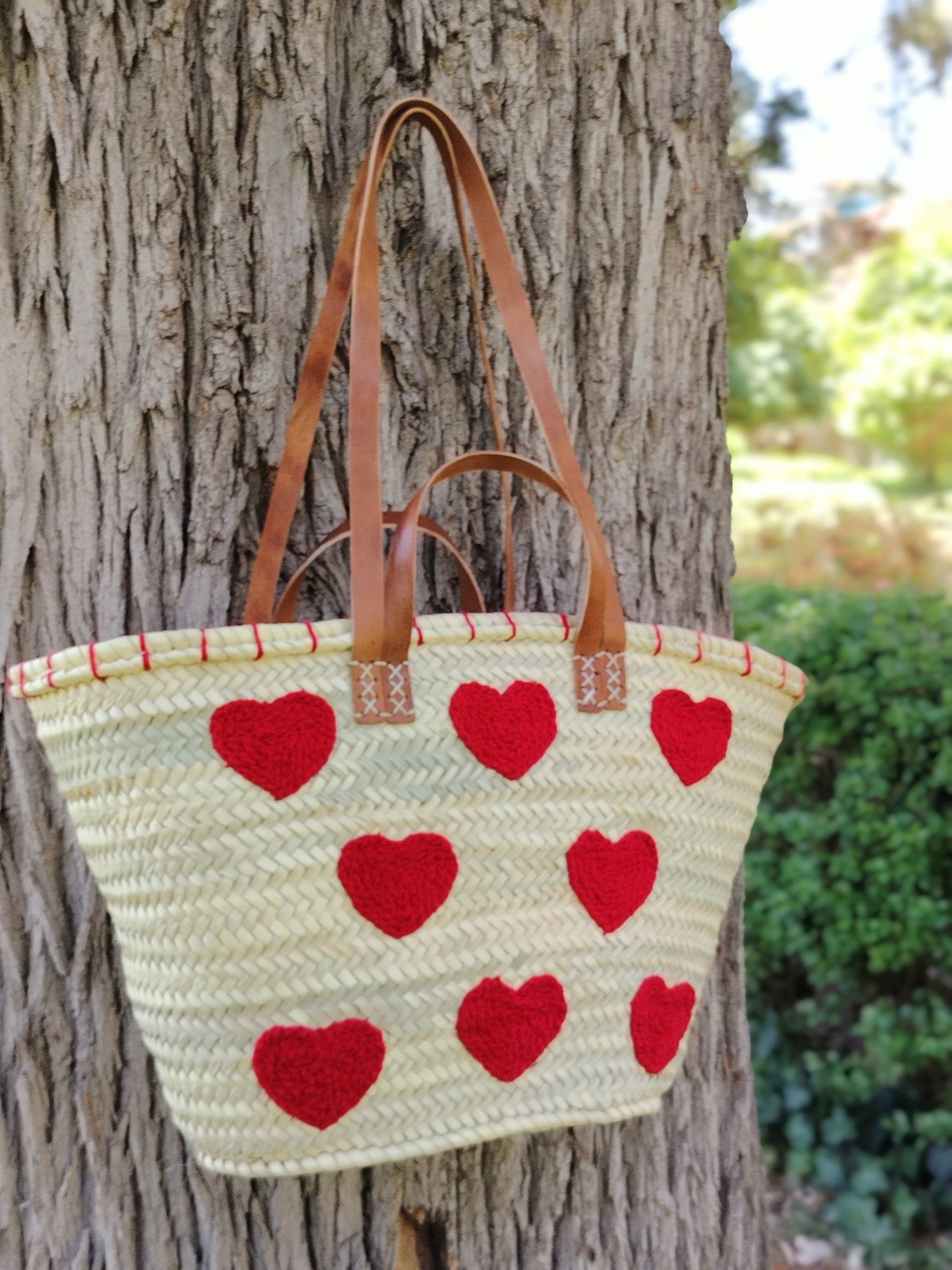Handwoven straw tote with red crochet hearts and leather handles. Eco-friendly, artisan-made, and perfect for markets, gifting, or seasonal outings.