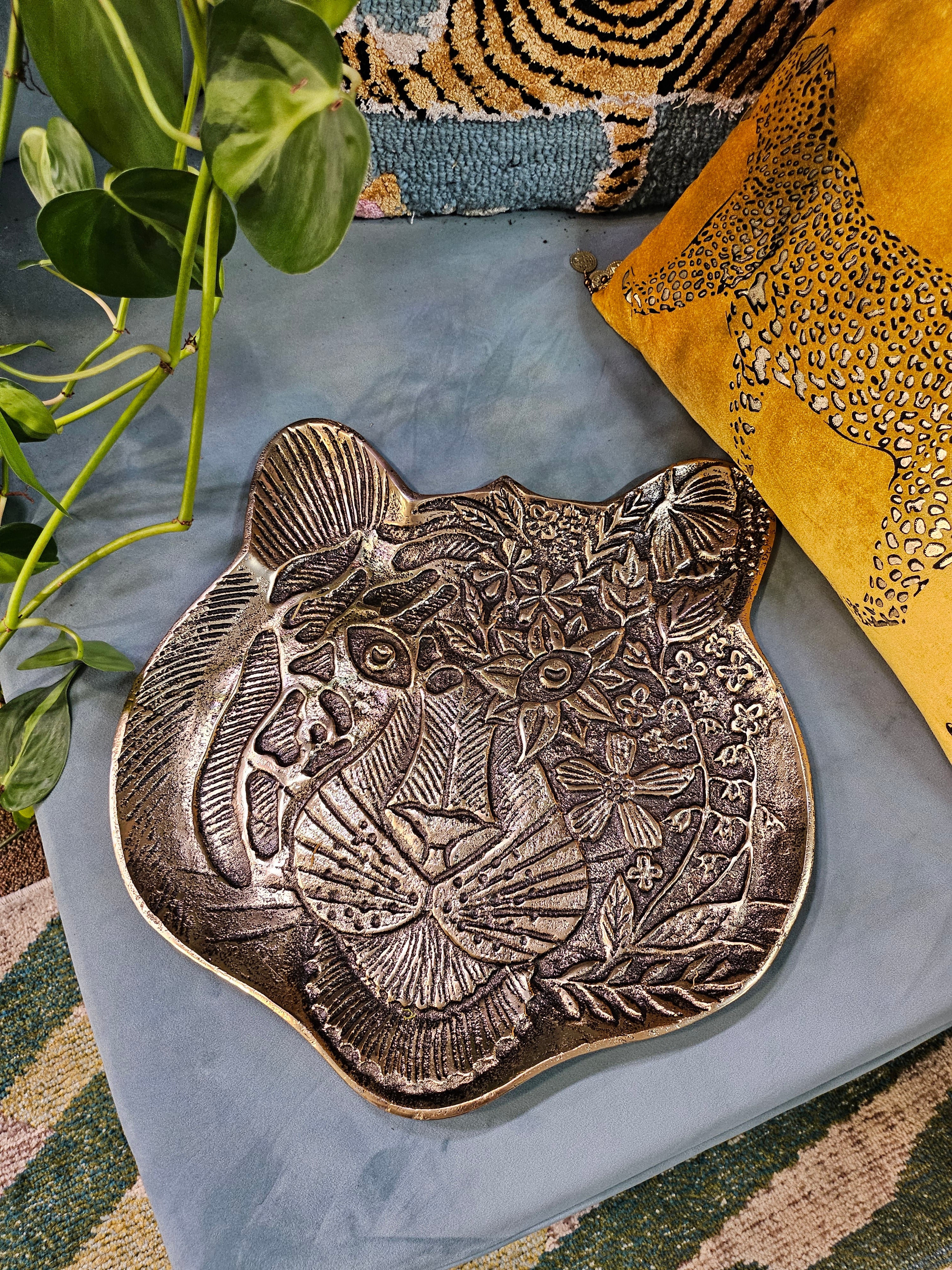 The Tiger Embossed Metal Tray is a luxurious and durable 16 cm x 14.5 cm catchall dish with a golden finish and intricate tiger head design. Perfect for organizing jewelry, keys, or coins, it adds a regal touch to any space. Ideal as a functional decor piece or a thoughtful gift for art and animal lovers