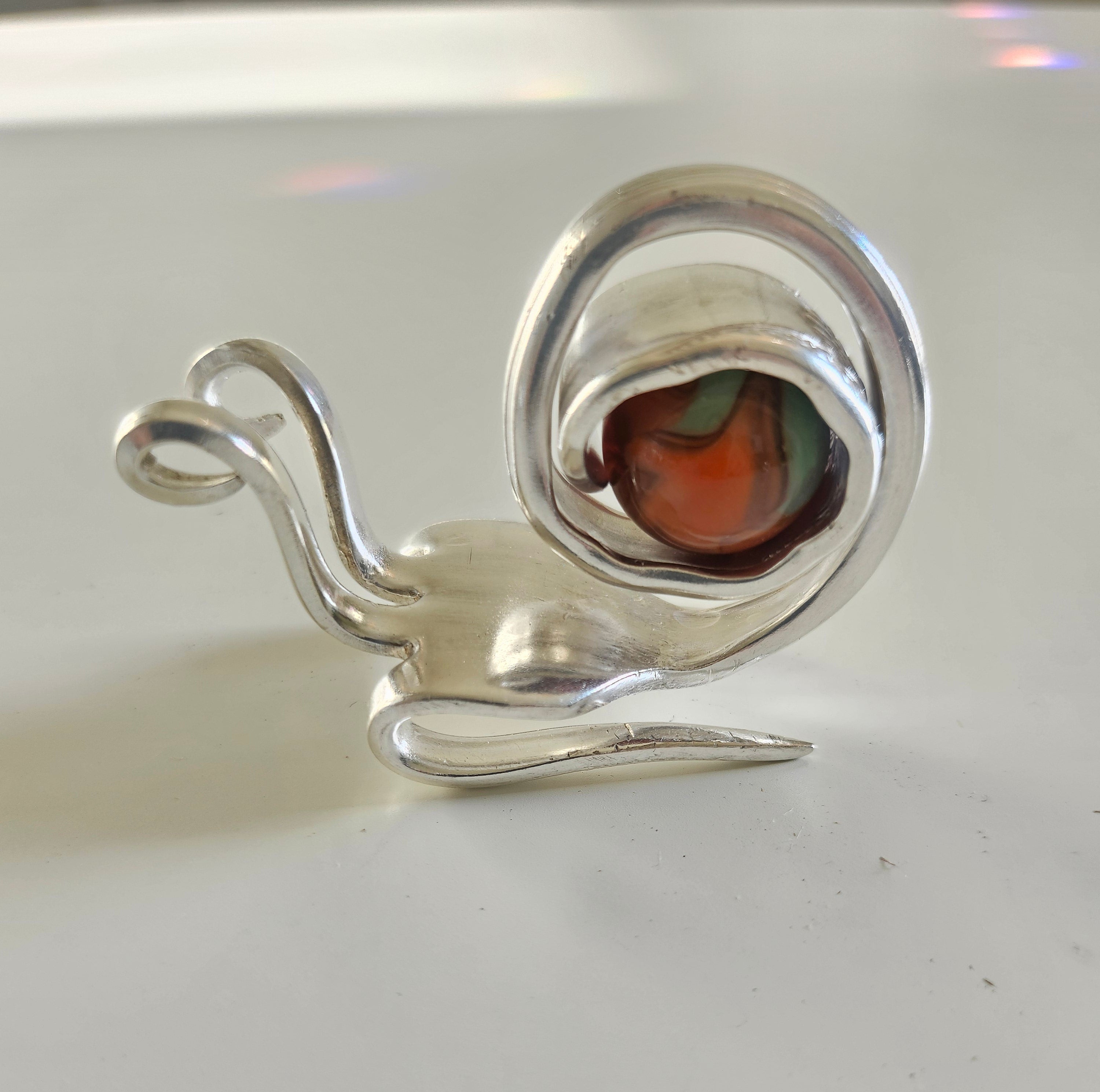 Handcrafted from vintage silverware, these whimsical snails feature shimmering glass orb shells—each a one-of-a-kind symbol of patience and charm.