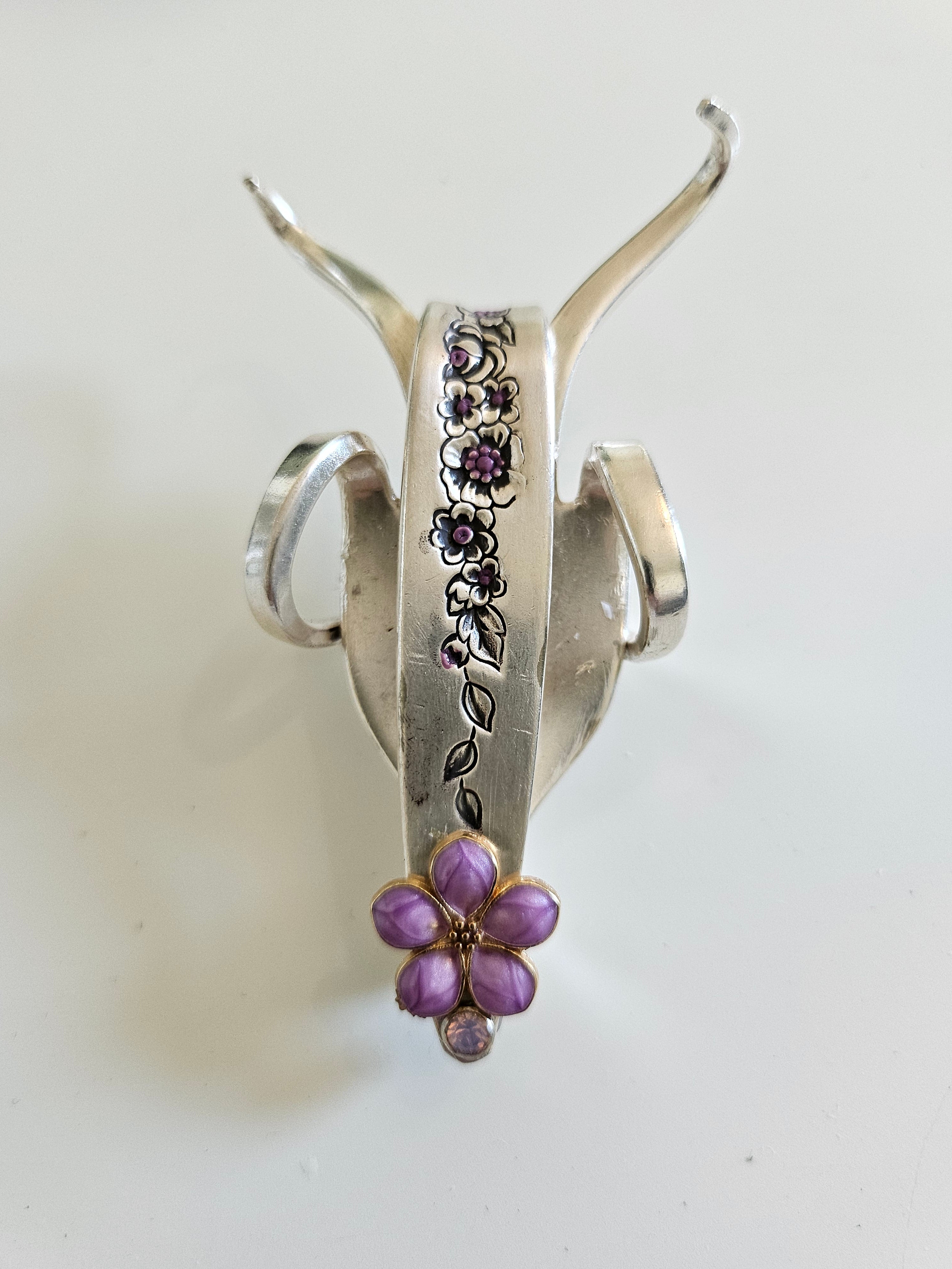 The Jeweled Lucky Fork Cricket is a whimsical, handcrafted sculpture made from repurposed vintage silverware. Each unique piece, shaped from antique forks, captures the charm of crickets—symbols of luck, prosperity, and protection. Adorned with jewels and aged patina, these one-of-a-kind collectibles add artistry, history, and positive energy to any space.