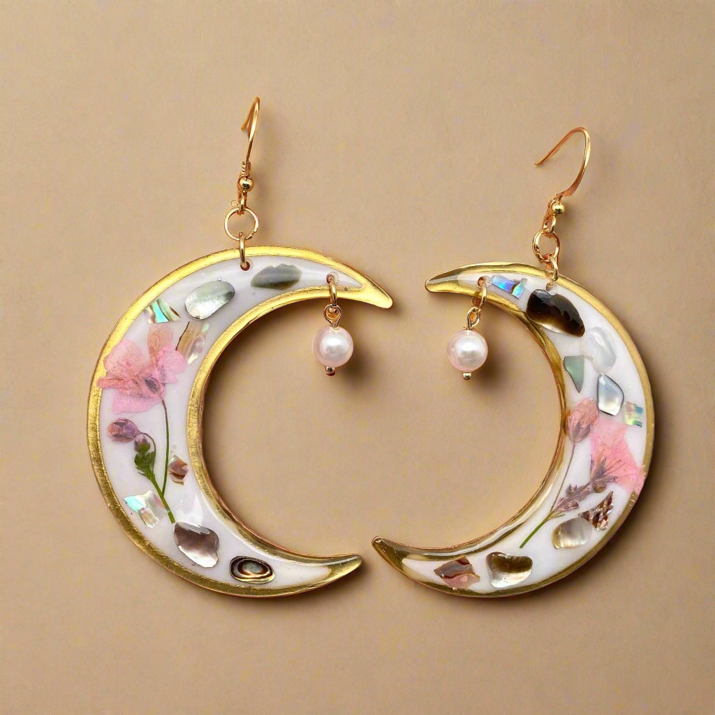 Lunar Bloom earrings with real pressed flowers in resin and 18K gold-plated brass. Bold, handmade floral statement jewelry in a 40mm x 66mm drop design.