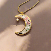 Moon-shaped pendant necklace with real pressed flowers and shell in resin, set in 18K gold-plated brass. Unique, handmade celestial floral jewelry.