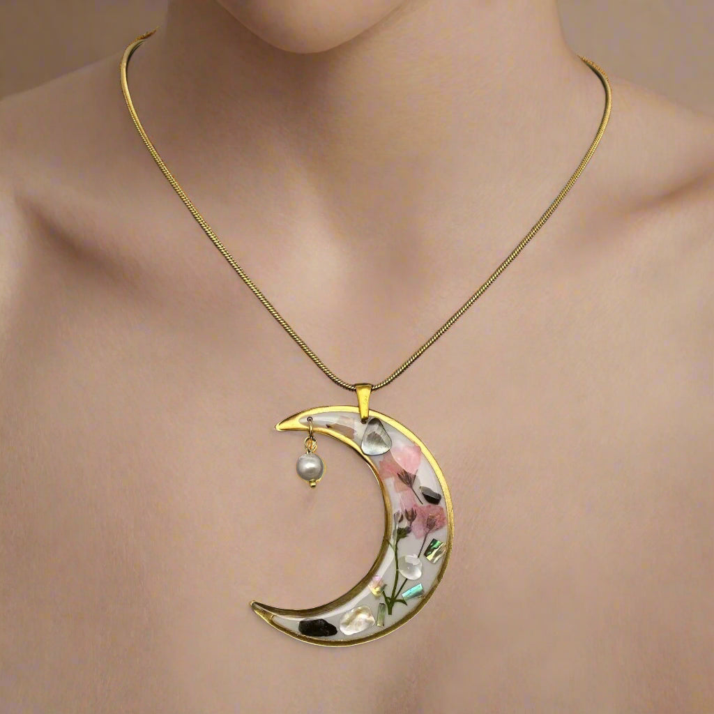 Moon-shaped pendant necklace with real pressed flowers and shell in resin, set in 18K gold-plated brass. Unique, handmade celestial floral jewelry.