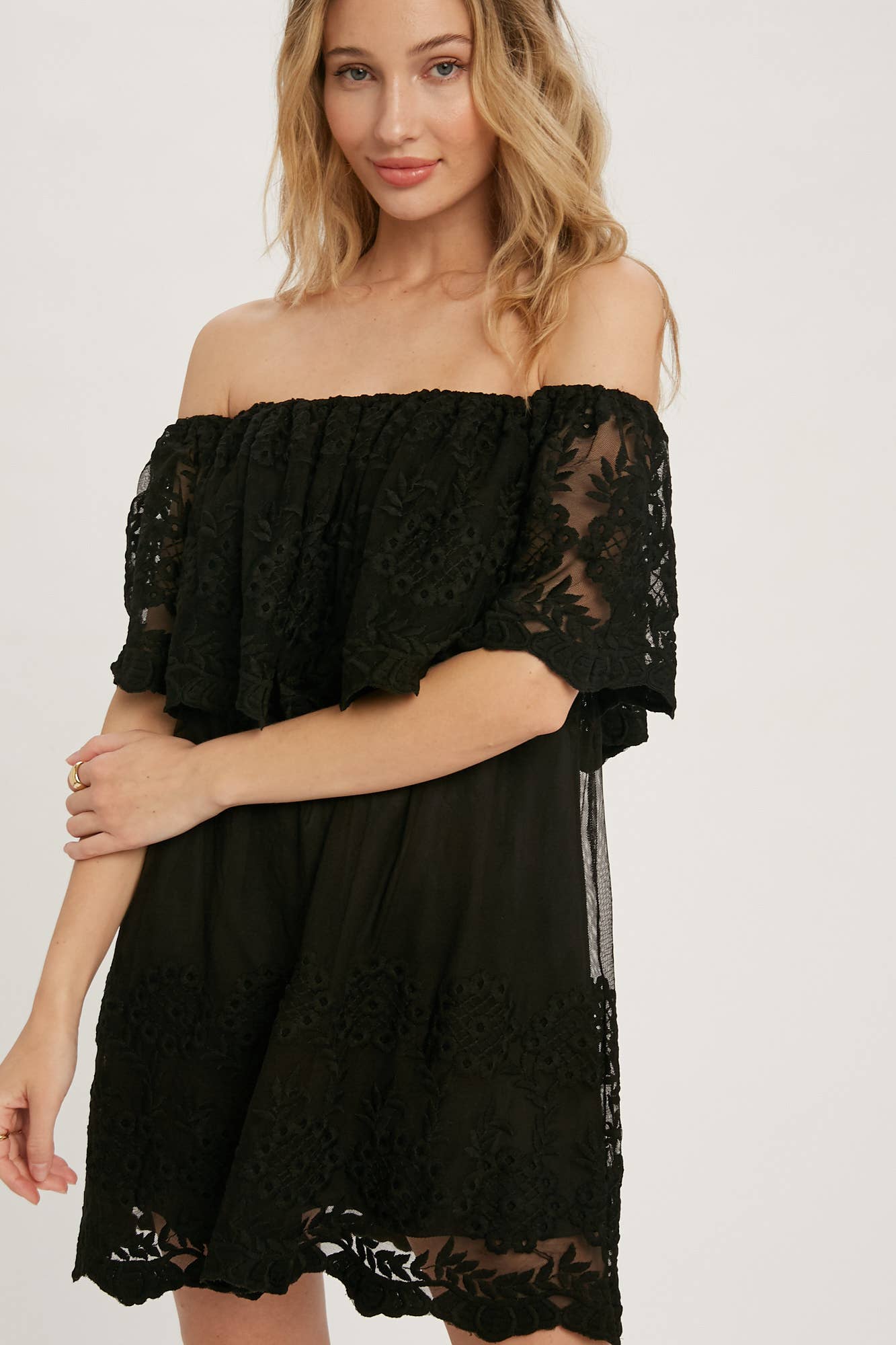 Off-the-shoulder floral lace mini dress with elastic neckline and swingy flounce silhouette. Romantic woven lace, scalloped hem, feminine fit.