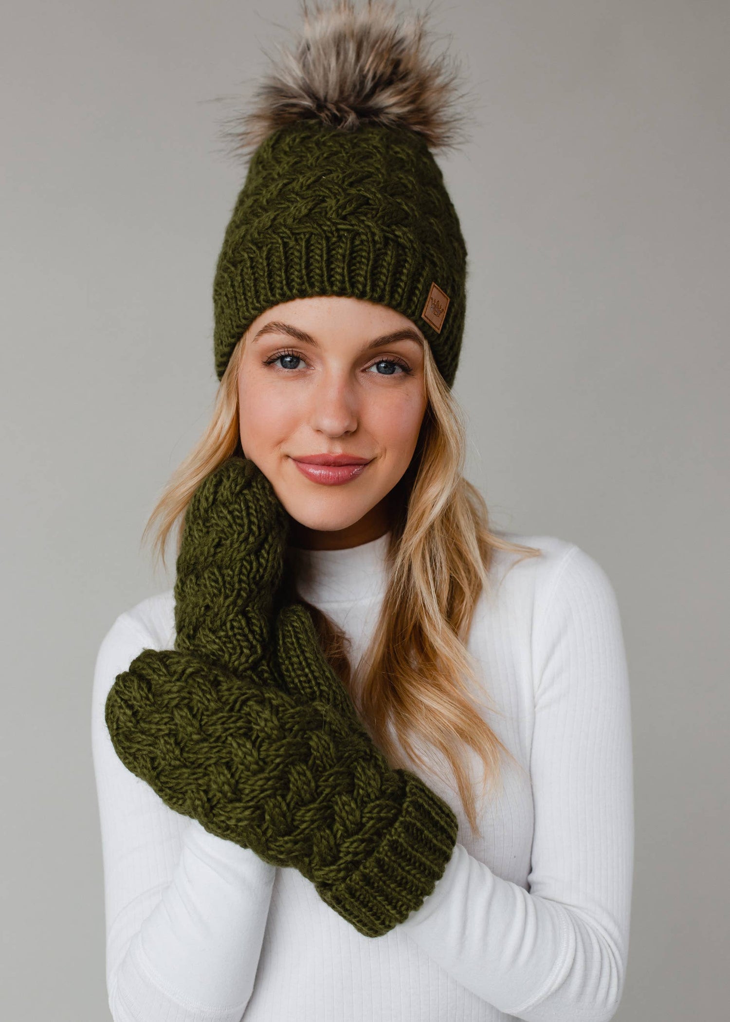 Olive green knit hat with natural faux fur pom. Cozy, stylish, and versatile—crafted from 100% acrylic for warmth and everyday boho-chic winter vibes.