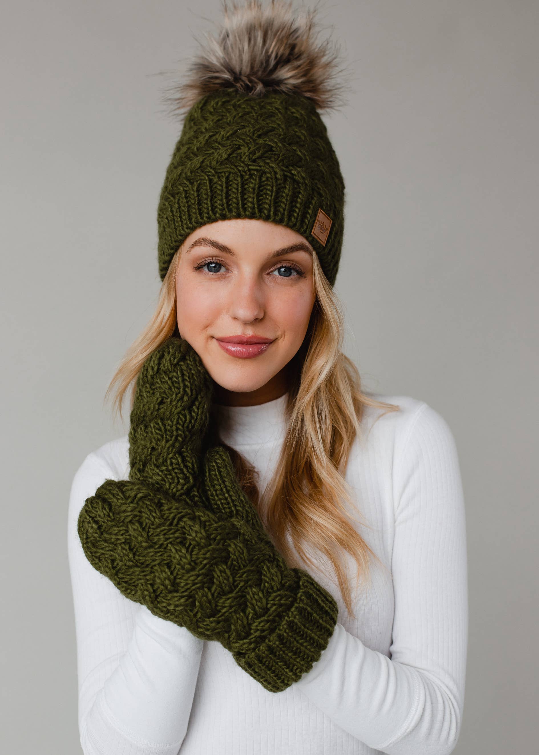 Olive green knit hat with natural faux fur pom. Cozy, stylish, and versatile—crafted from 100% acrylic for warmth and everyday boho-chic winter vibes.