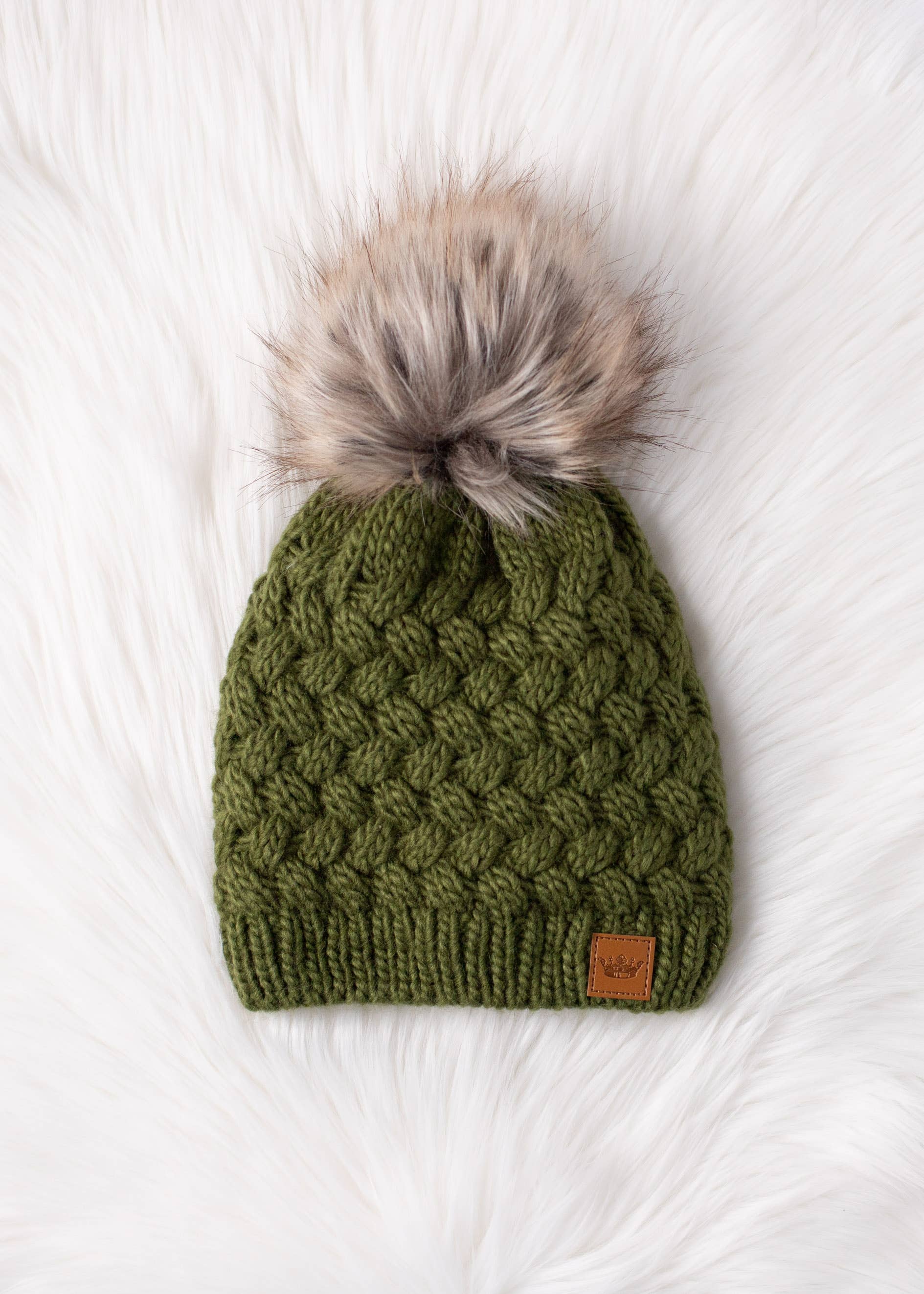 Olive green knit hat with natural faux fur pom. Cozy, stylish, and versatile—crafted from 100% acrylic for warmth and everyday boho-chic winter vibes.
