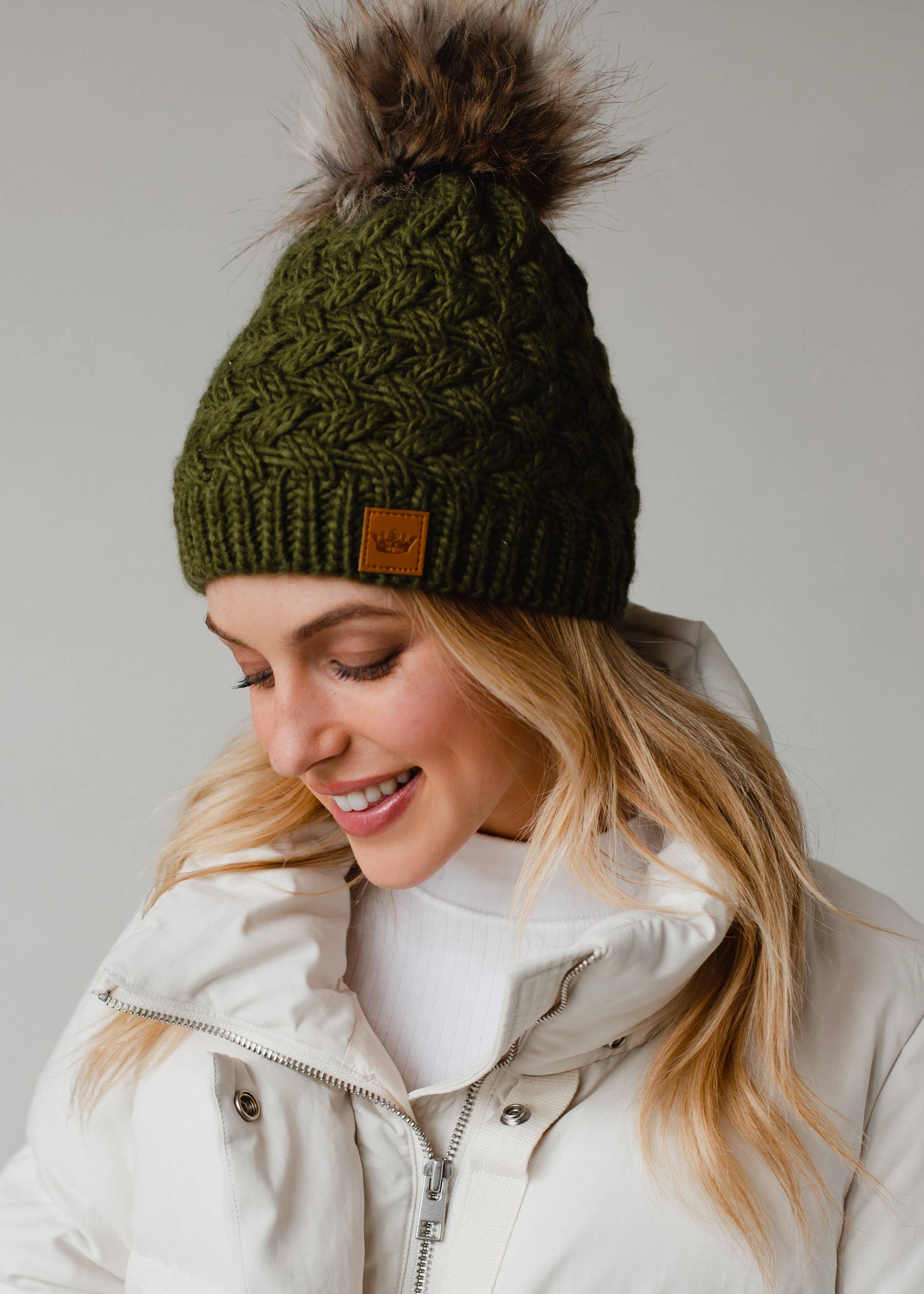 Olive green knit hat with natural faux fur pom. Cozy, stylish, and versatile—crafted from 100% acrylic for warmth and everyday boho-chic winter vibes.