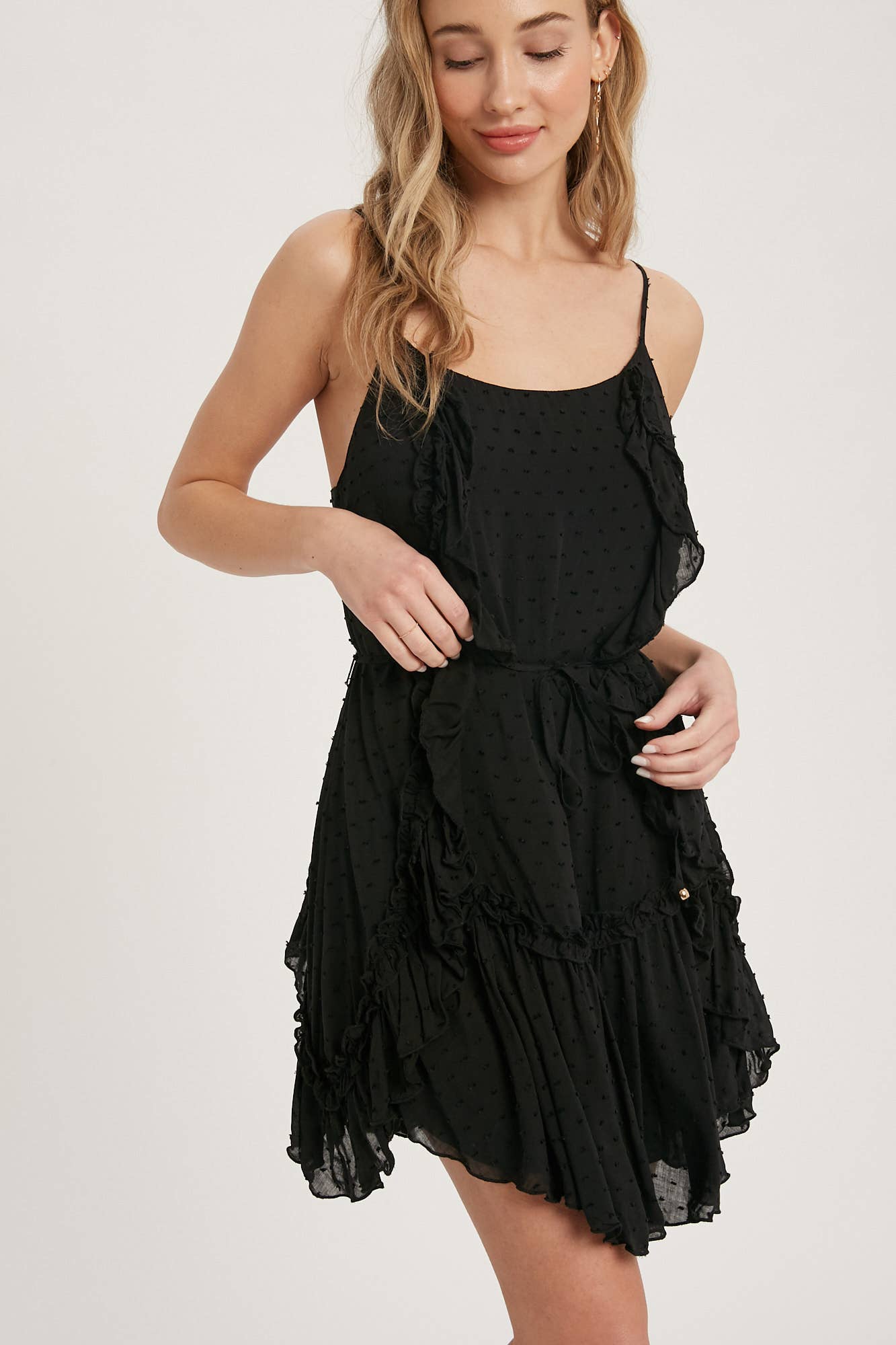 Swiss dot mini dress with ruffle details, lace-up back, adjustable straps & waist tie. Lightweight rayon, perfect for warm days & effortlessly chic looks.