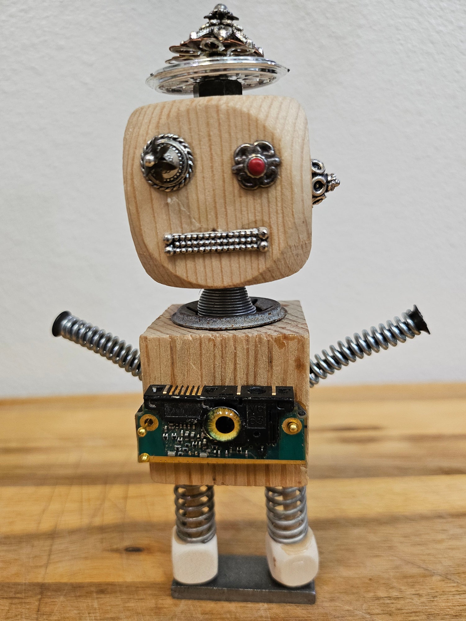 The Handmade Wood Block Steampunk Robot is a unique, decorative figurine crafted from wood with an aged, rustic look. Each robot is one-of-a-kind for display only. Includes a heart-shaped balloon. Available in various sizes, it&