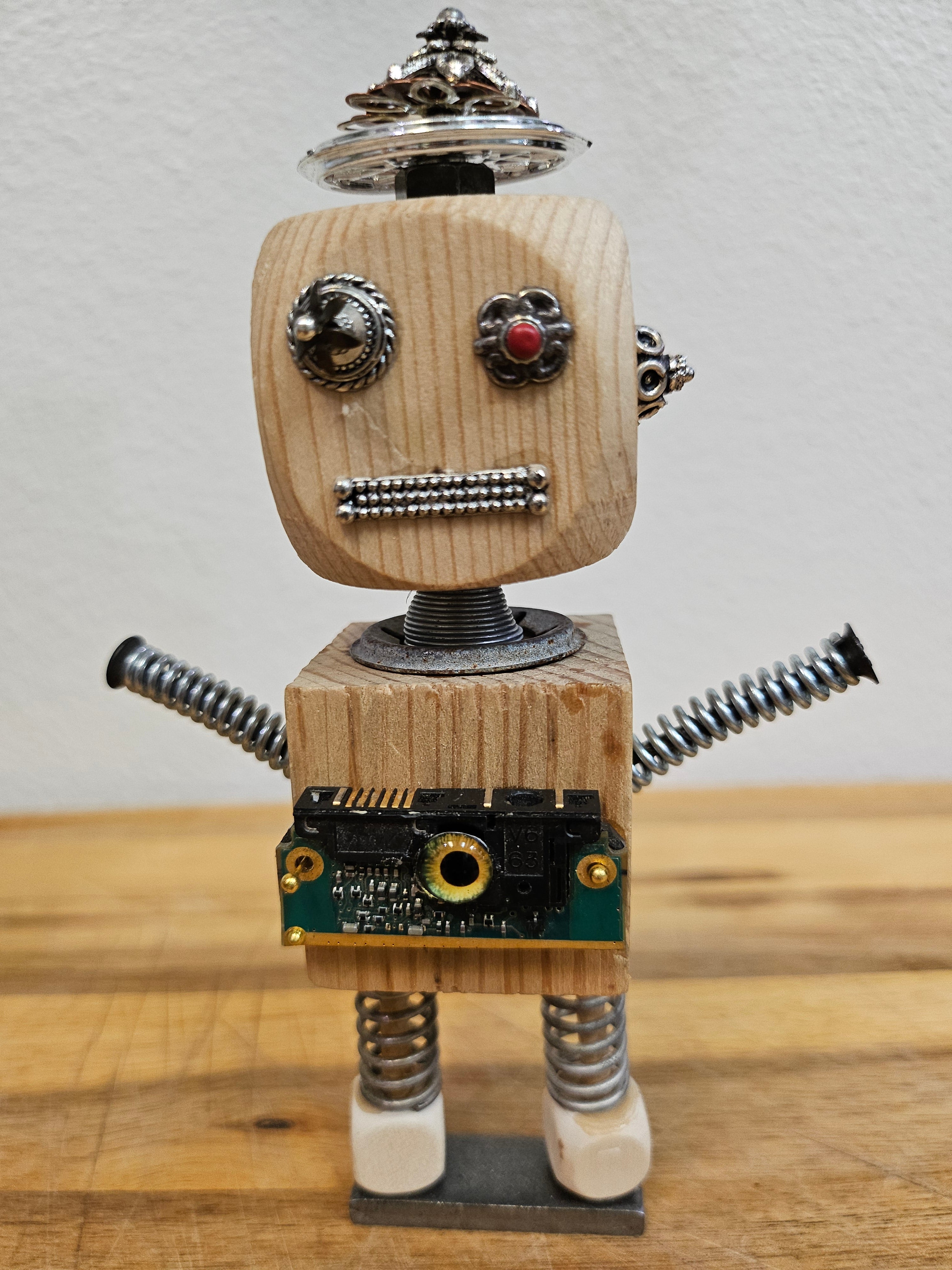 The Handmade Wood Block Steampunk Robot is a unique, decorative figurine crafted from wood with an aged, rustic look. Each robot is one-of-a-kind for display only. Includes a heart-shaped balloon. Available in various sizes, it&