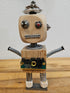 The Handmade Wood Block Steampunk Robot is a unique, decorative figurine crafted from wood with an aged, rustic look. Each robot is one-of-a-kind for display only. Includes a heart-shaped balloon. Available in various sizes, it&