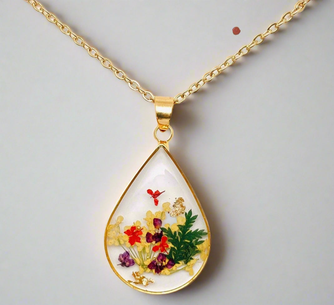 Teardrop necklace with real pressed dried flowers in resin. Unique floral charm with stainless steel chain and copper frame. Nature-inspired and handcrafted.