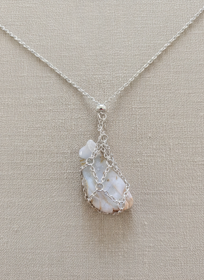 A versatile Crystal and Rock Cage Necklace with an adjustable metal pendant. Swap in your favorite gemstones or charms for a personalized, mystical accessory.