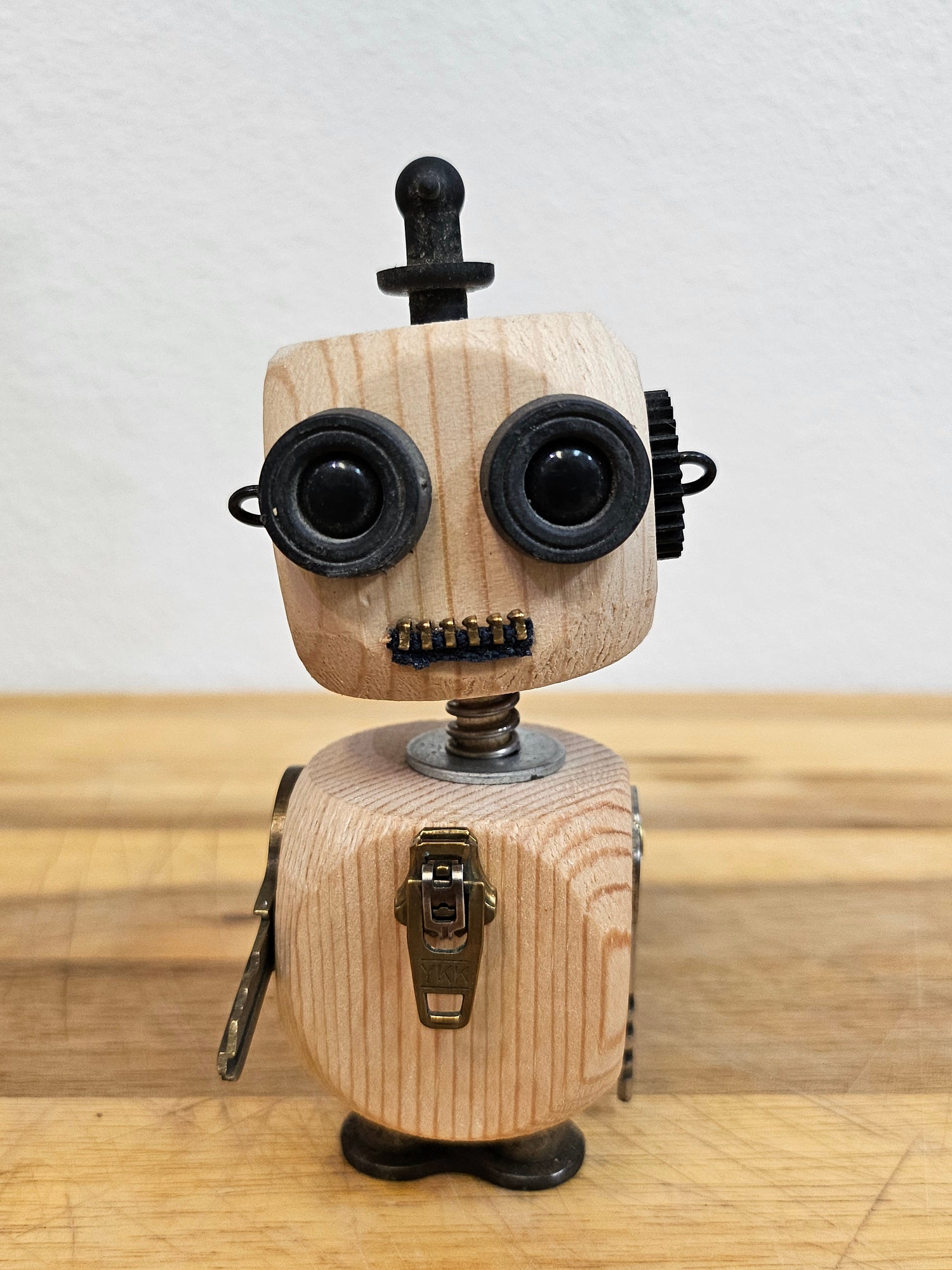 The Handmade Wood Block Steampunk Robot is a unique, decorative figurine crafted from wood with an aged, rustic look. Each robot is one-of-a-kind for display only. Includes a heart-shaped balloon. Available in various sizes, it&