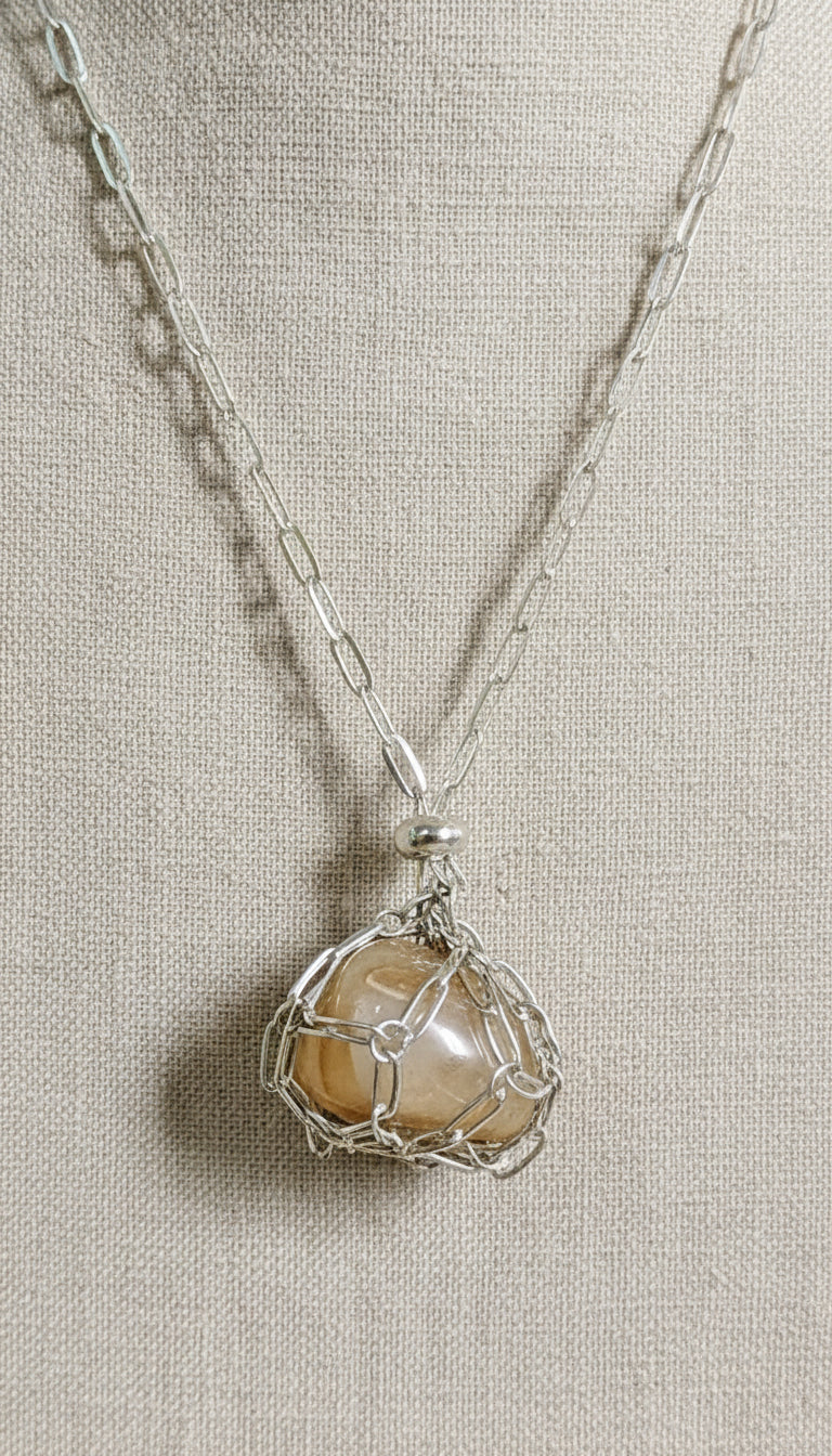 A versatile Crystal and Rock Cage Necklace with an adjustable metal pendant. Swap in your favorite gemstones or charms for a personalized, mystical accessory.