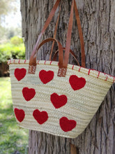 Handwoven straw tote with red crochet hearts and leather handles. Eco-friendly, artisan-made, and perfect for markets, gifting, or seasonal outings.
