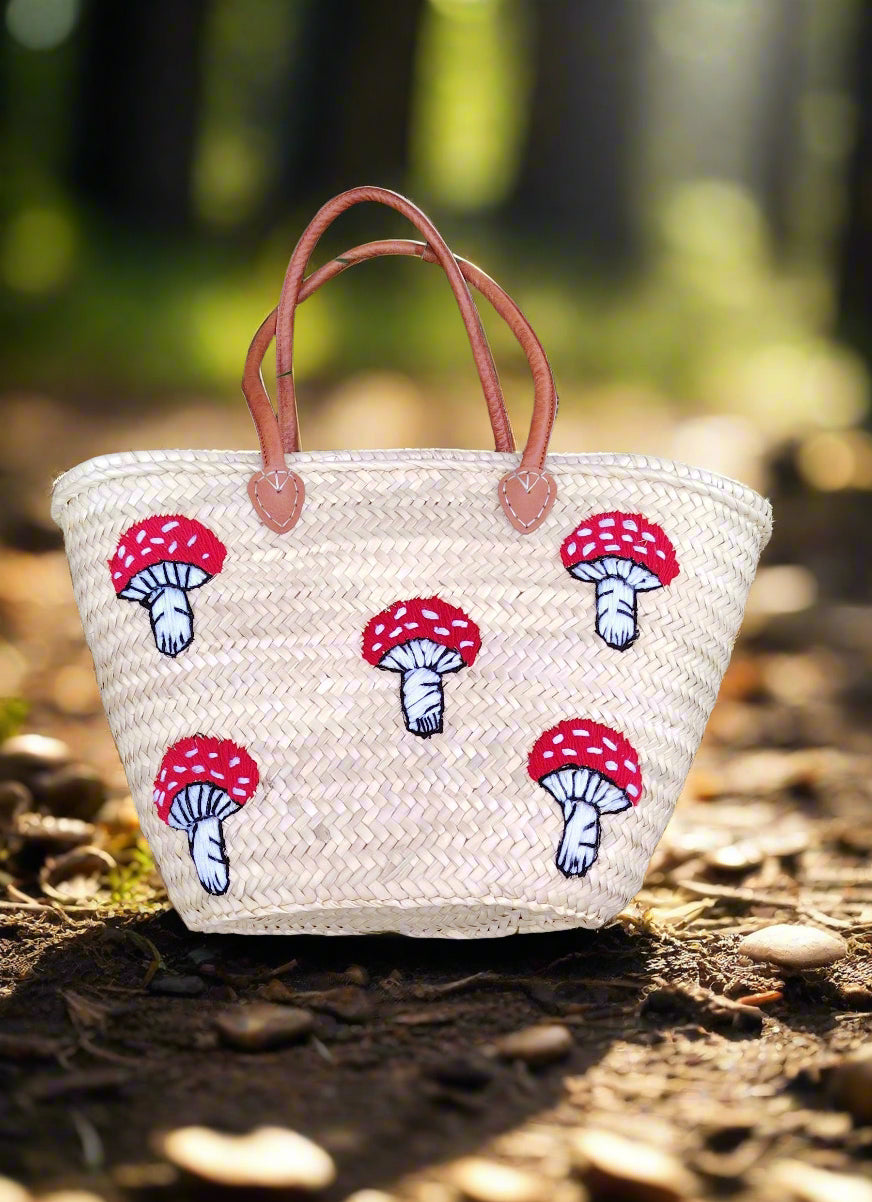 Whimsical straw tote with red mushroom embroidery, leather handles & eco-friendly palm straw. Perfect for market trips, beach days, or unique gifting.