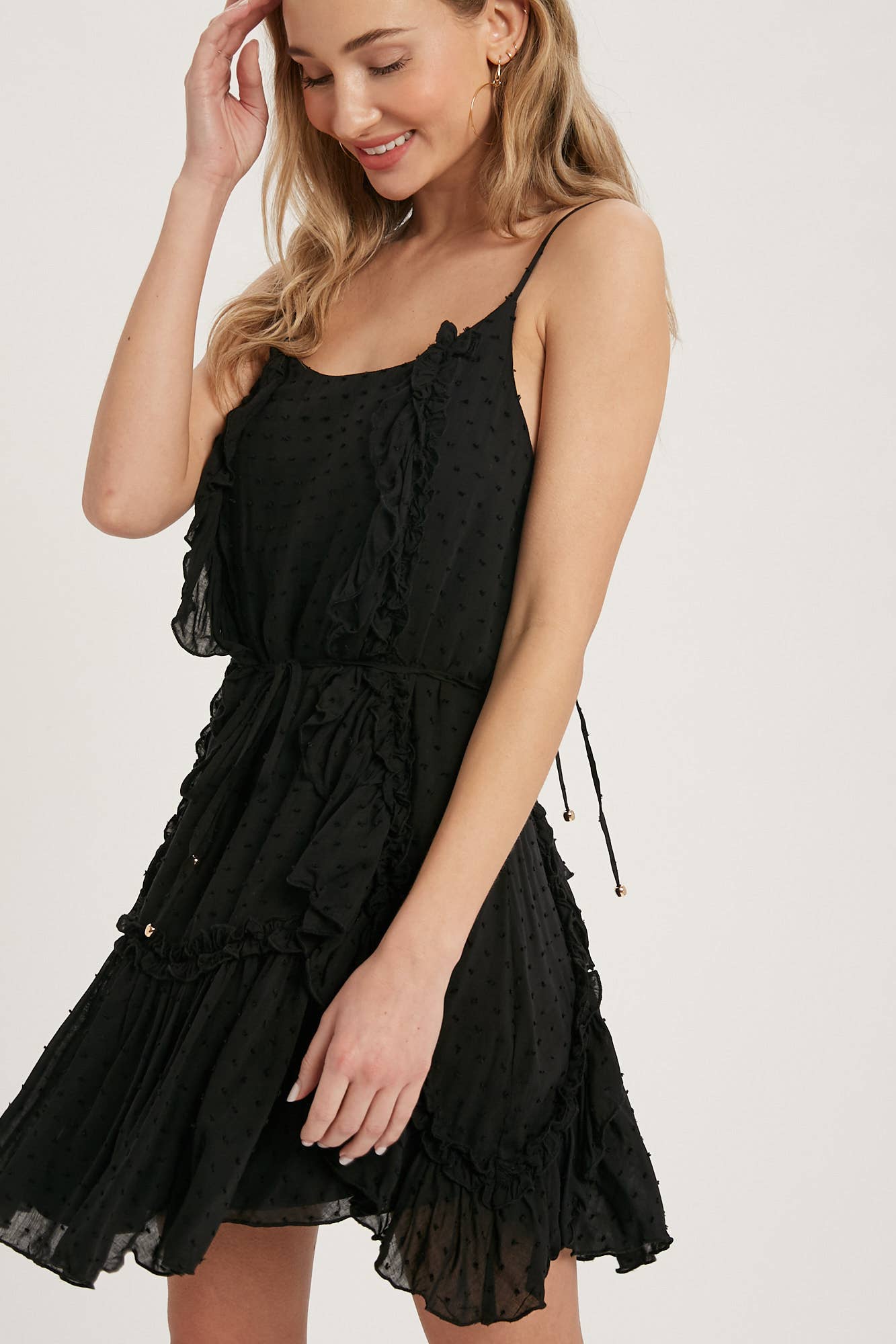 Swiss dot mini dress with ruffle details, lace-up back, adjustable straps & waist tie. Lightweight rayon, perfect for warm days & effortlessly chic looks.